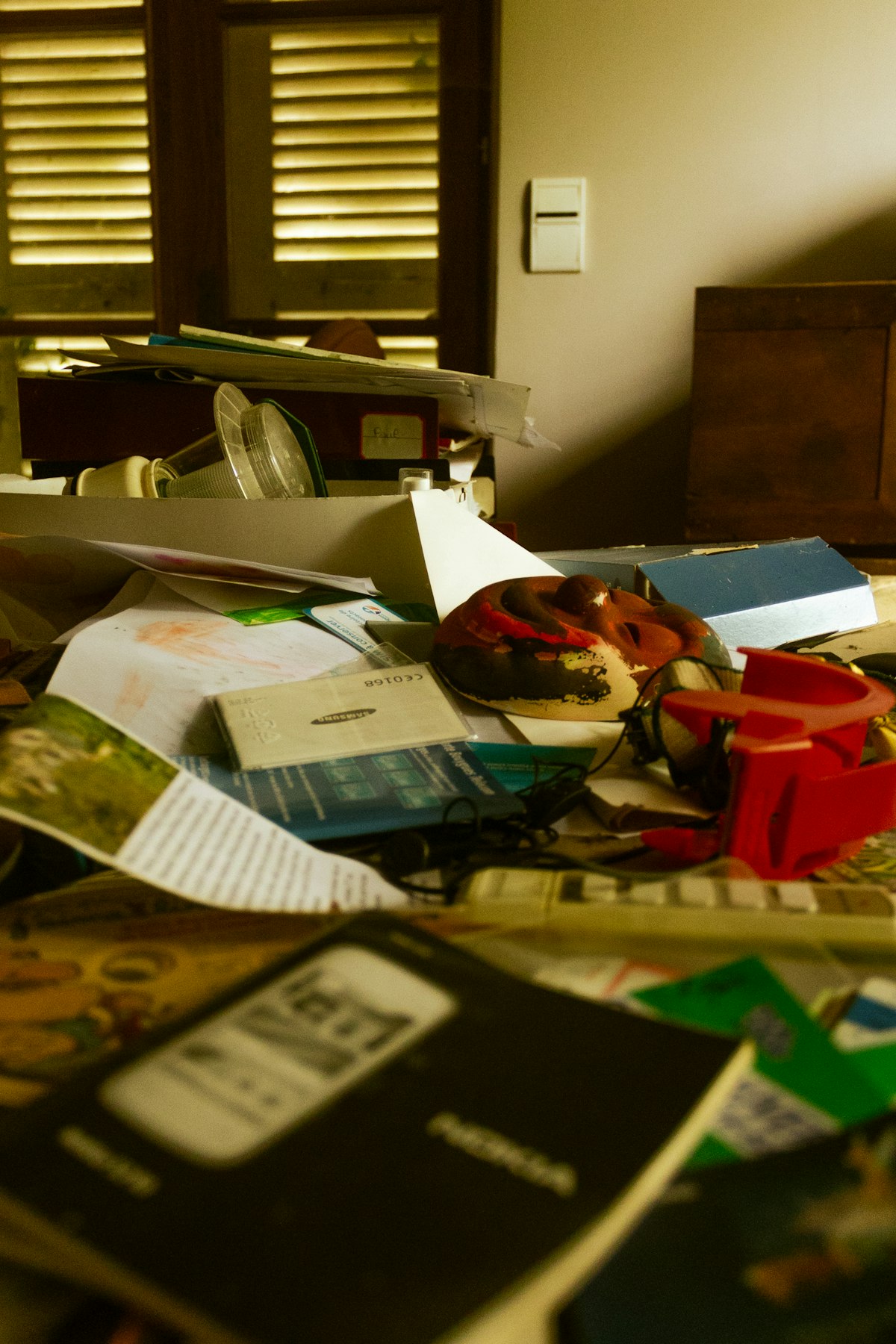 A cluttered desk covered in scattered papers, books and odds and ends