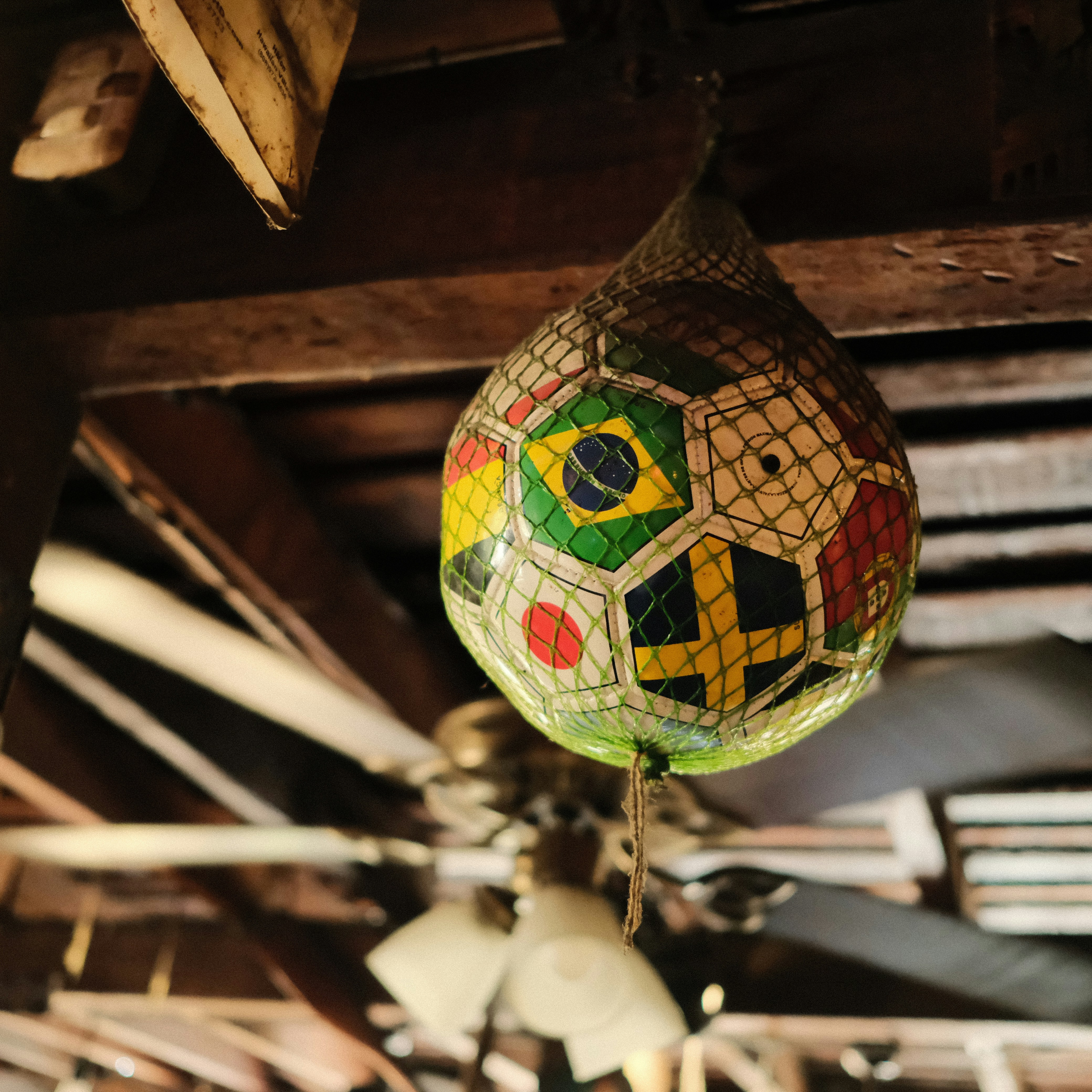 International flag soccer ball hanging from a rustic wooden ceiling.