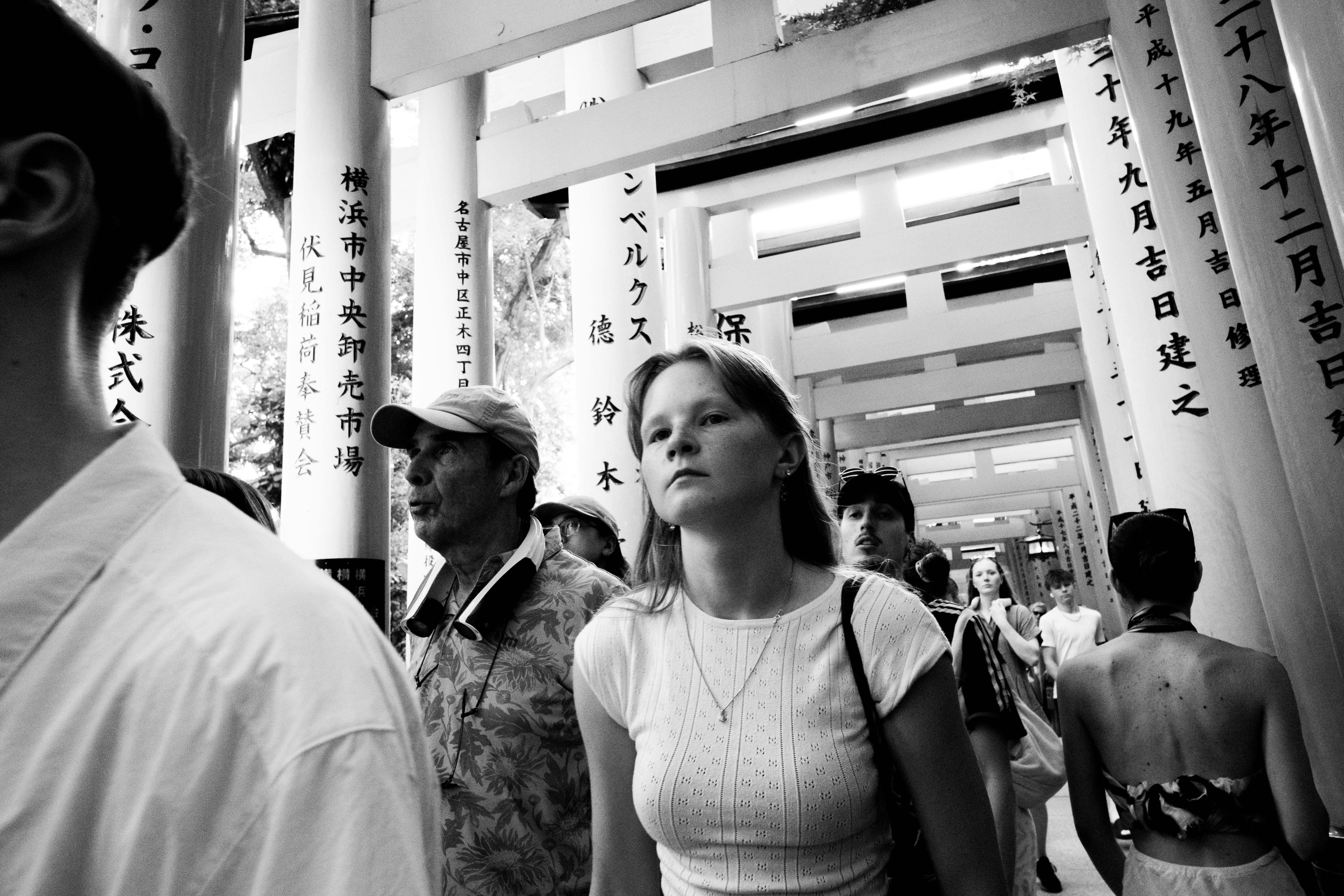 People walk through a corridor of traditional japanese gates.