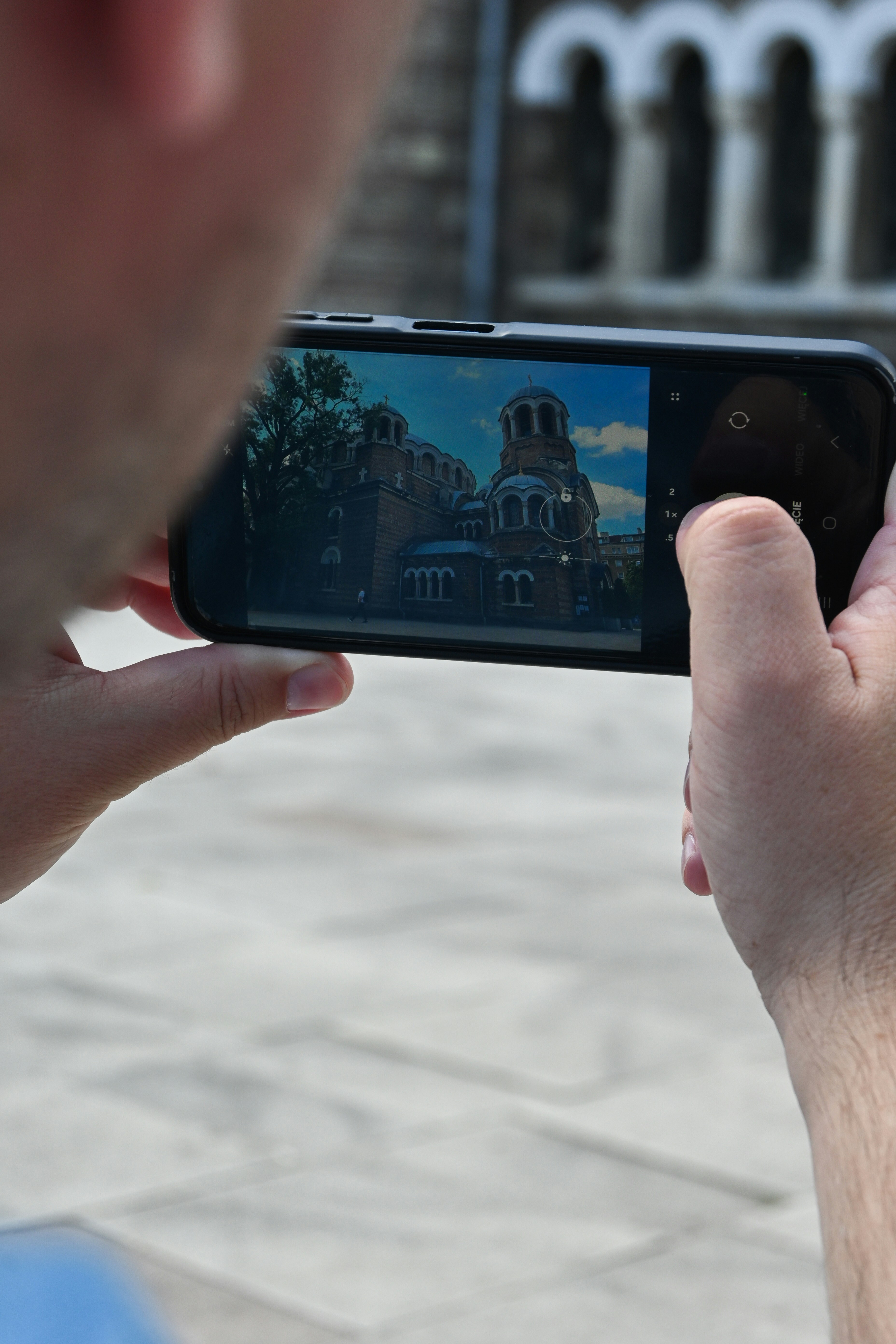 Person captures a church building on a smartphone screen.