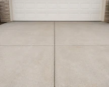 A concrete driveway in front of a white garage door.