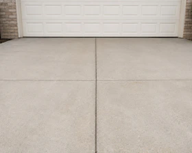 A concrete driveway in front of a white garage door.
