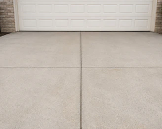 A concrete driveway in front of a white garage door