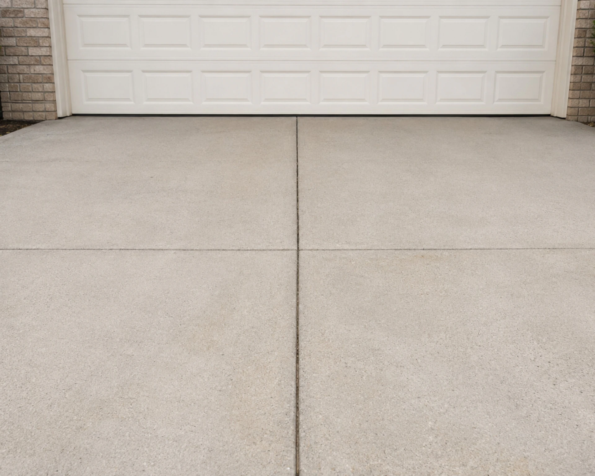A concrete driveway in front of a white garage door.