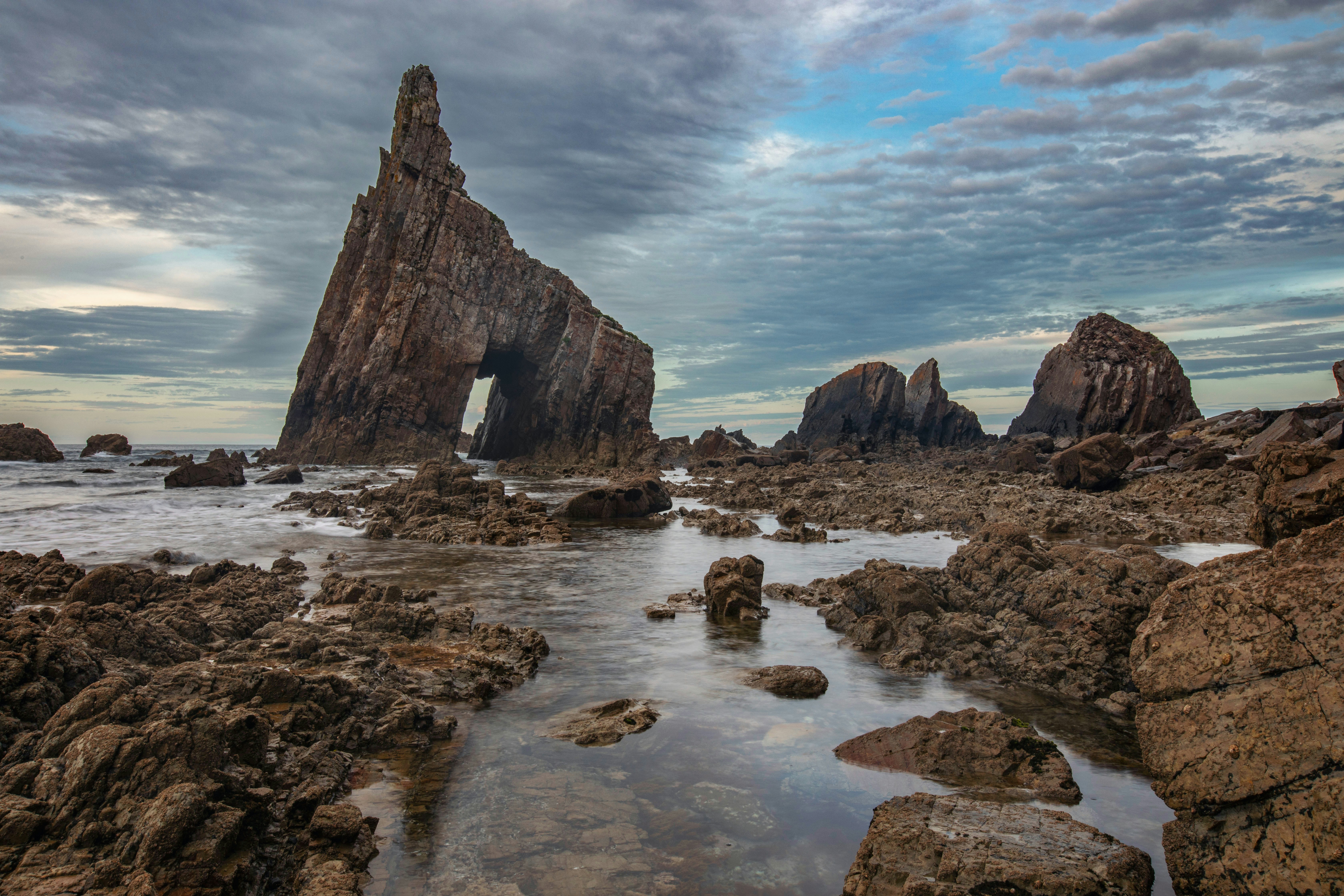 Dramatic rocky coastline with sea stacks under a cloudy sky.