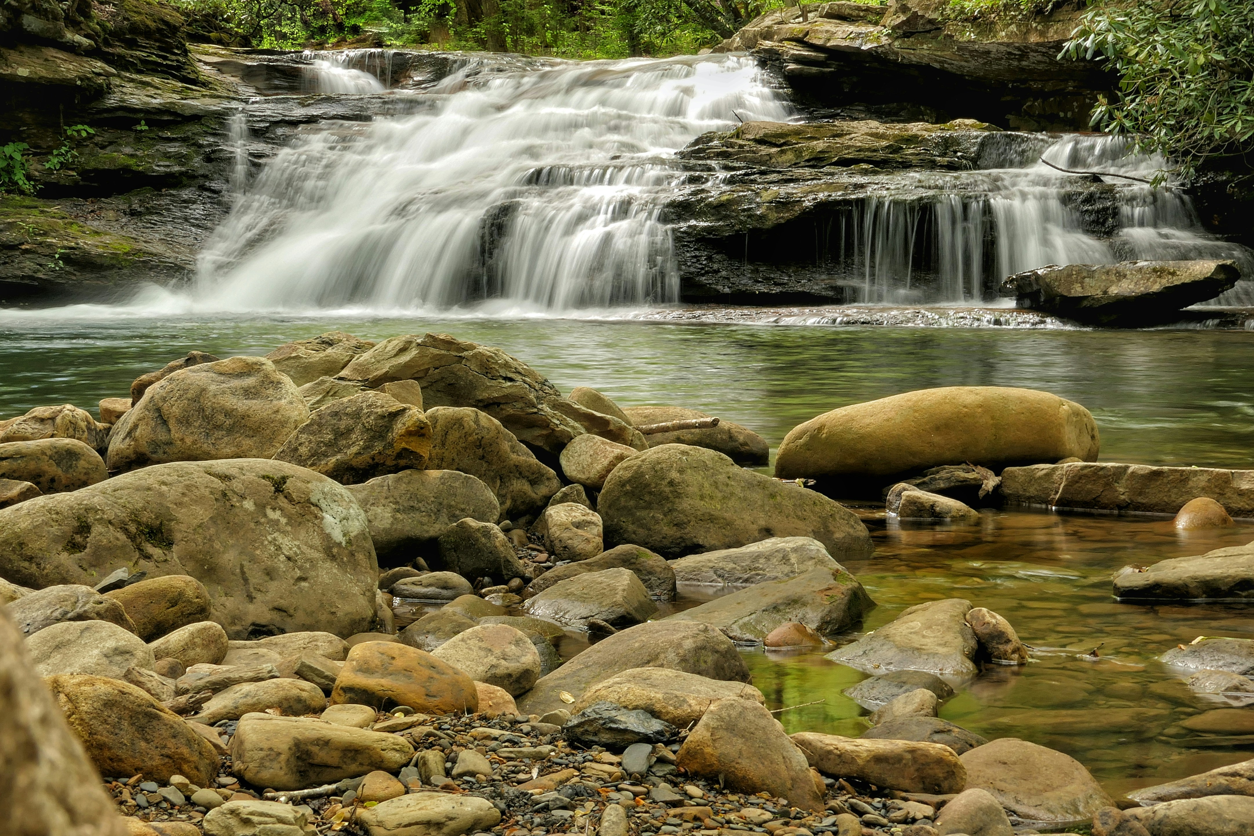 A beautiful waterfall cascades over rocks into a serene stream.