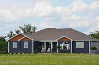 A single-story dark blue house with a green lawn