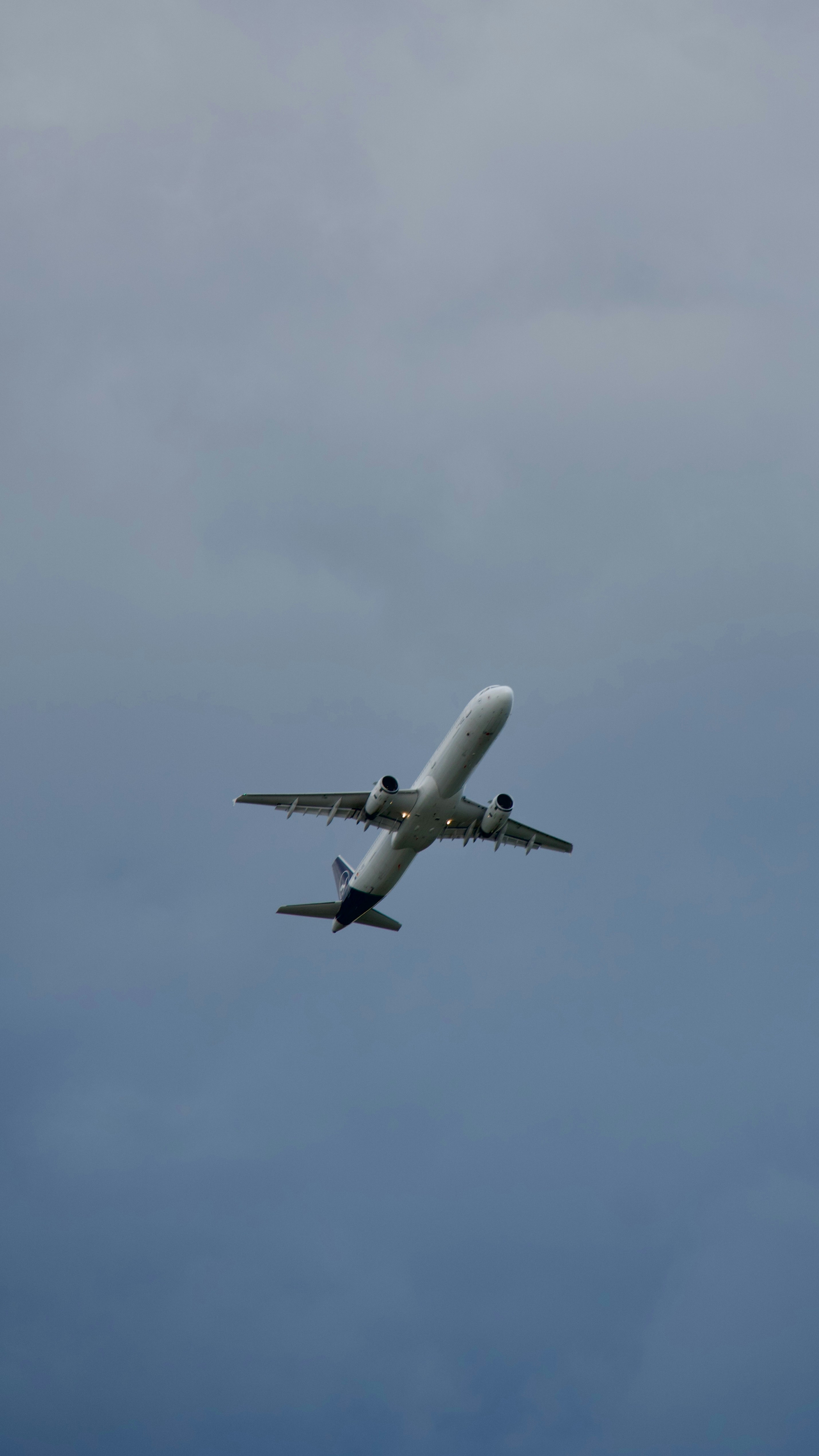 Passenger airplane flying overhead against a cloudy blue sky.