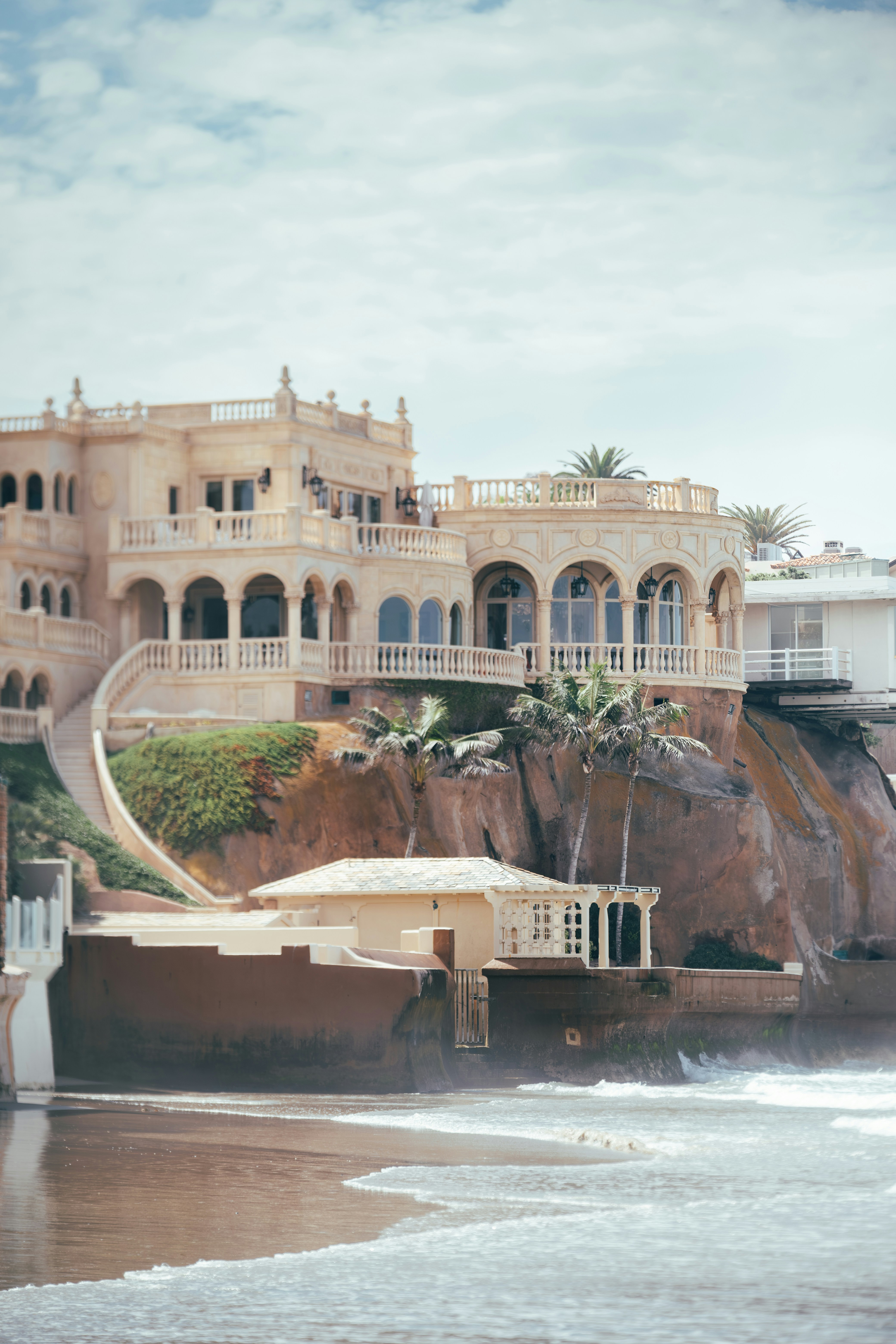 Mansão ornamentada em um penhasco acima de uma praia com ondas