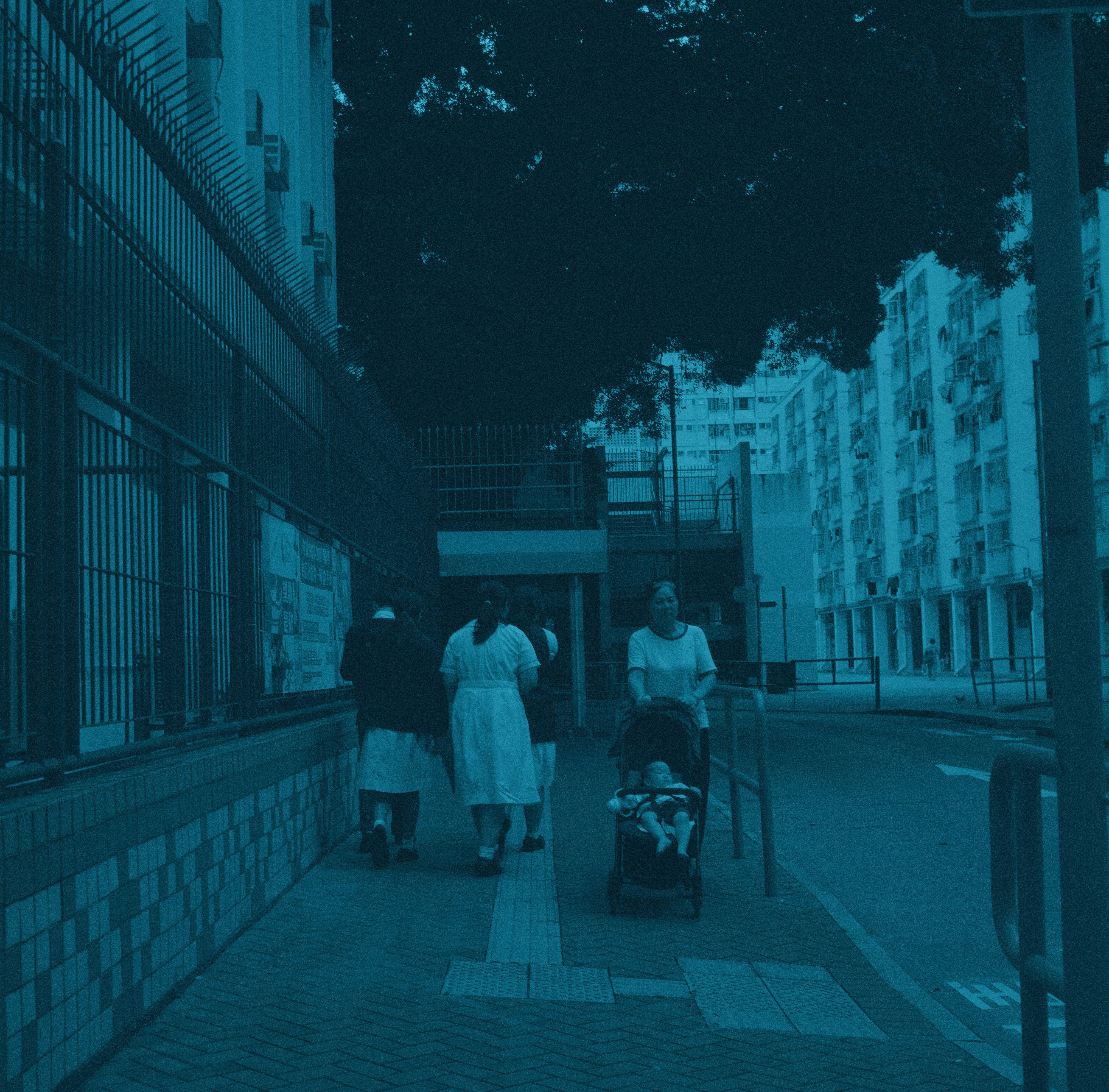 Three people walk on a sidewalk, one pushing a stroller.
