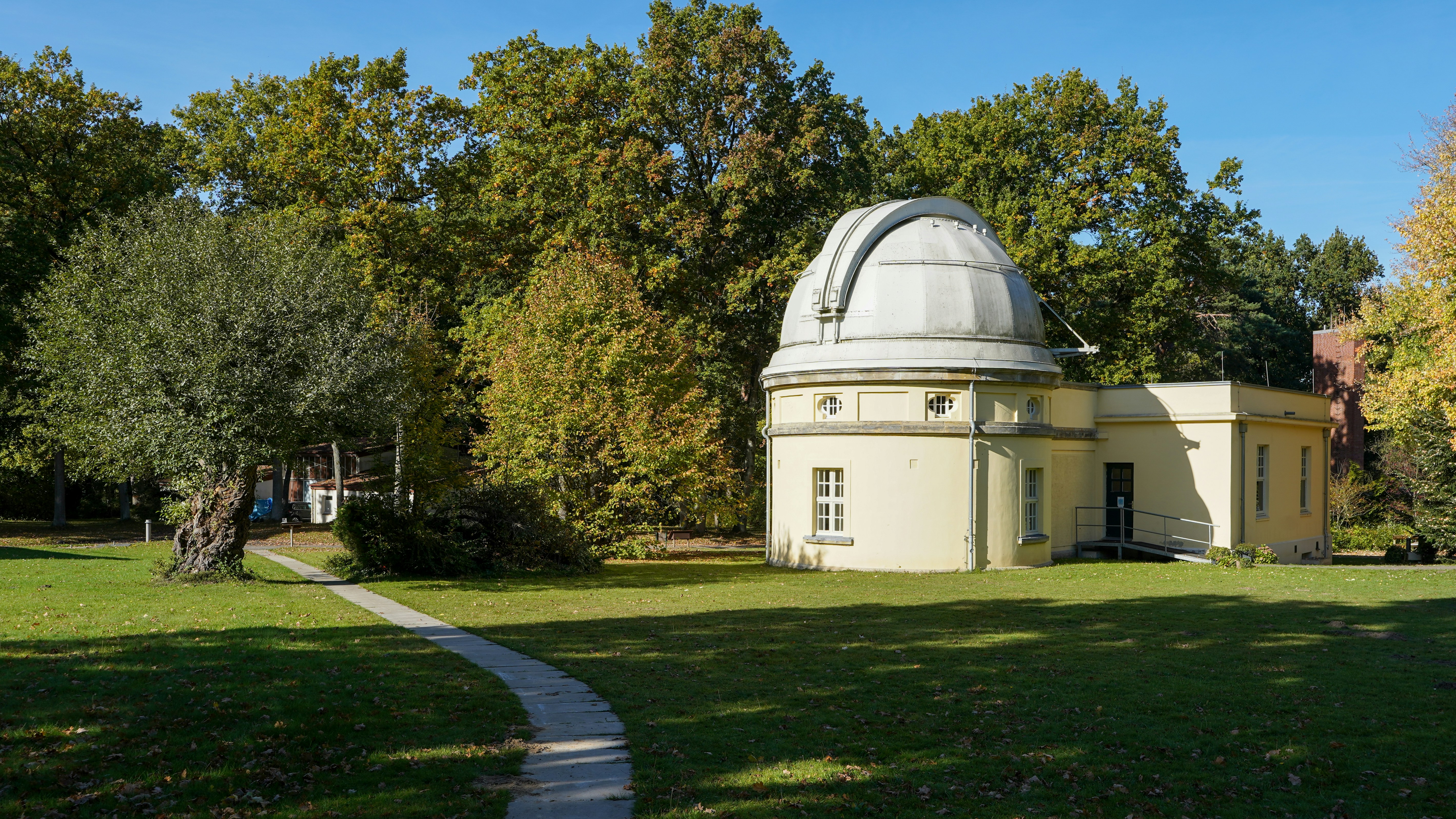 Ein Observatoriumsgebäude, umgeben von Bäumen und einem gewundenen Weg.