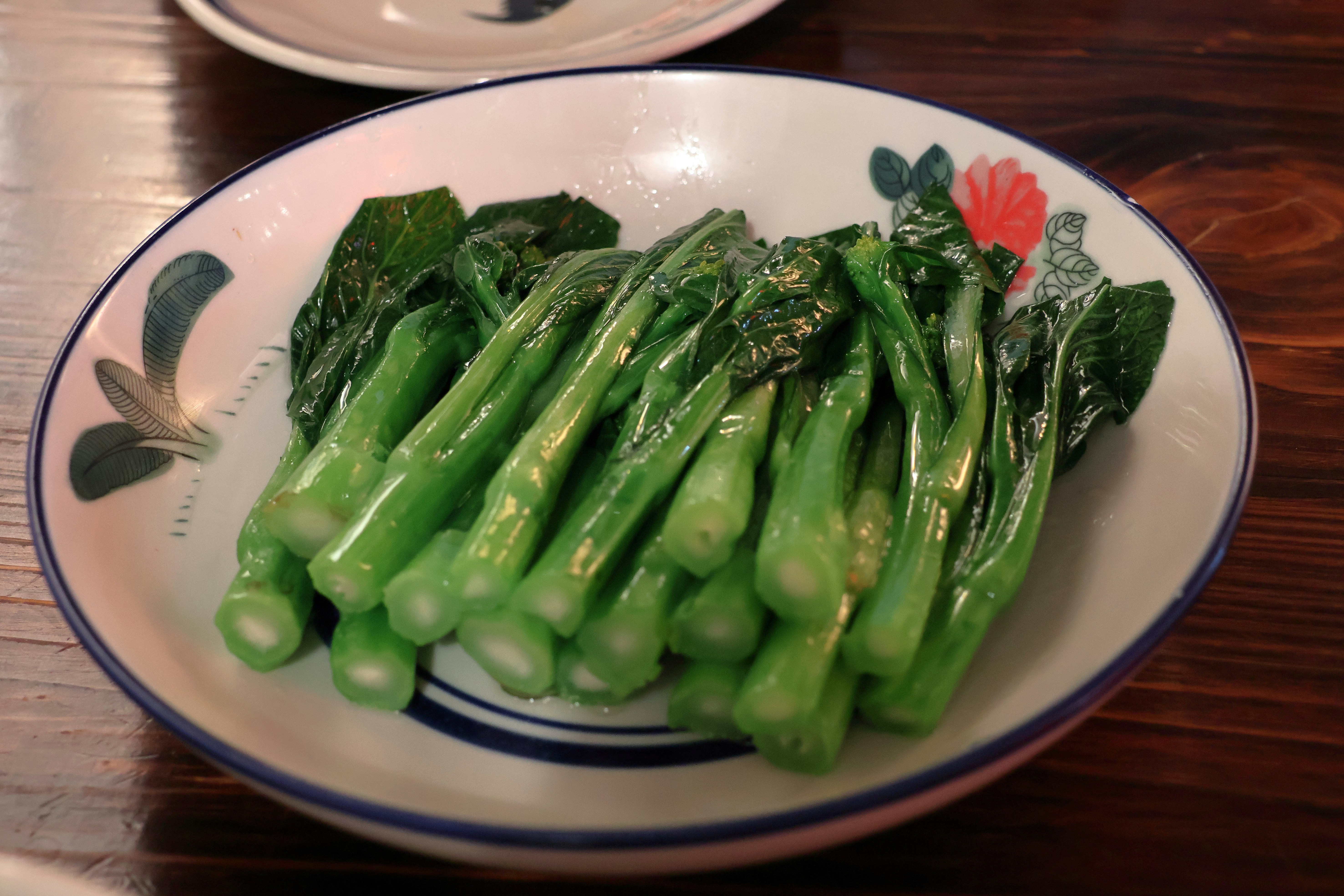 A plate of cooked green chinese broccoli.