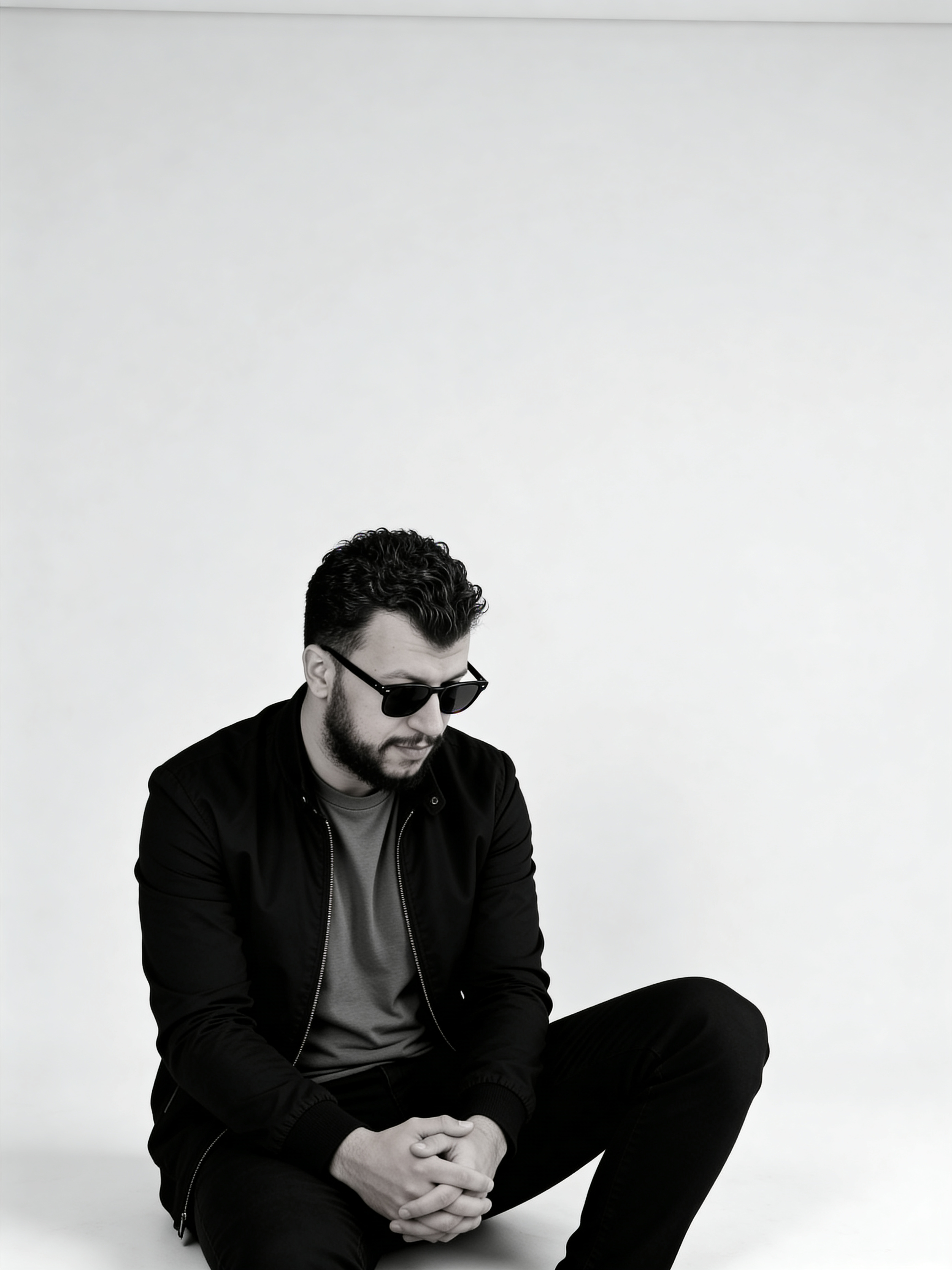 Man with beard and sunglasses sitting.