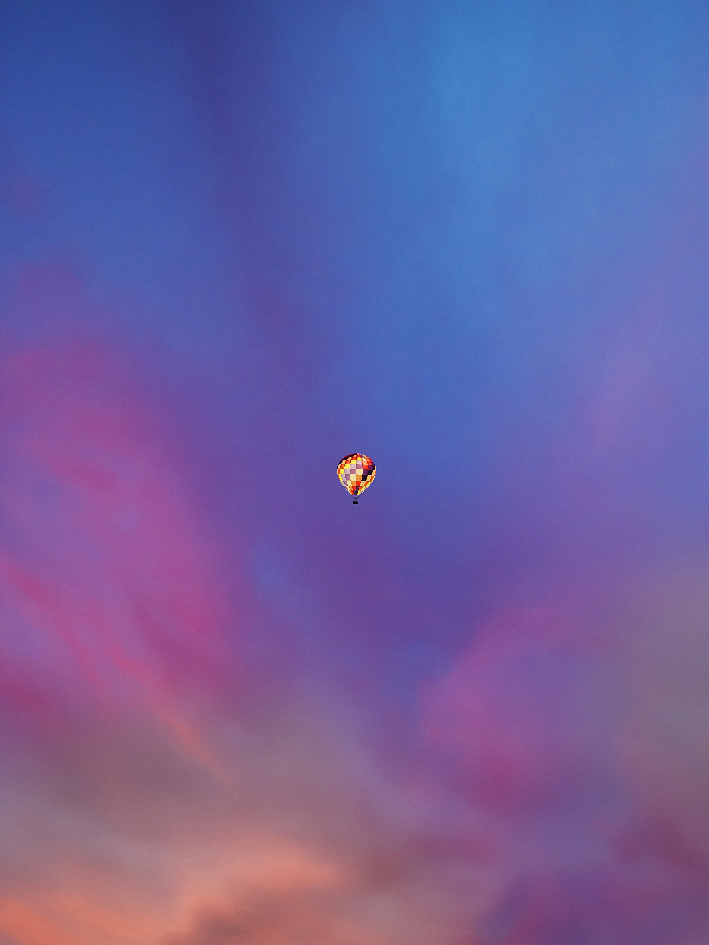 A hot air balloon floats in a vibrant sunset sky