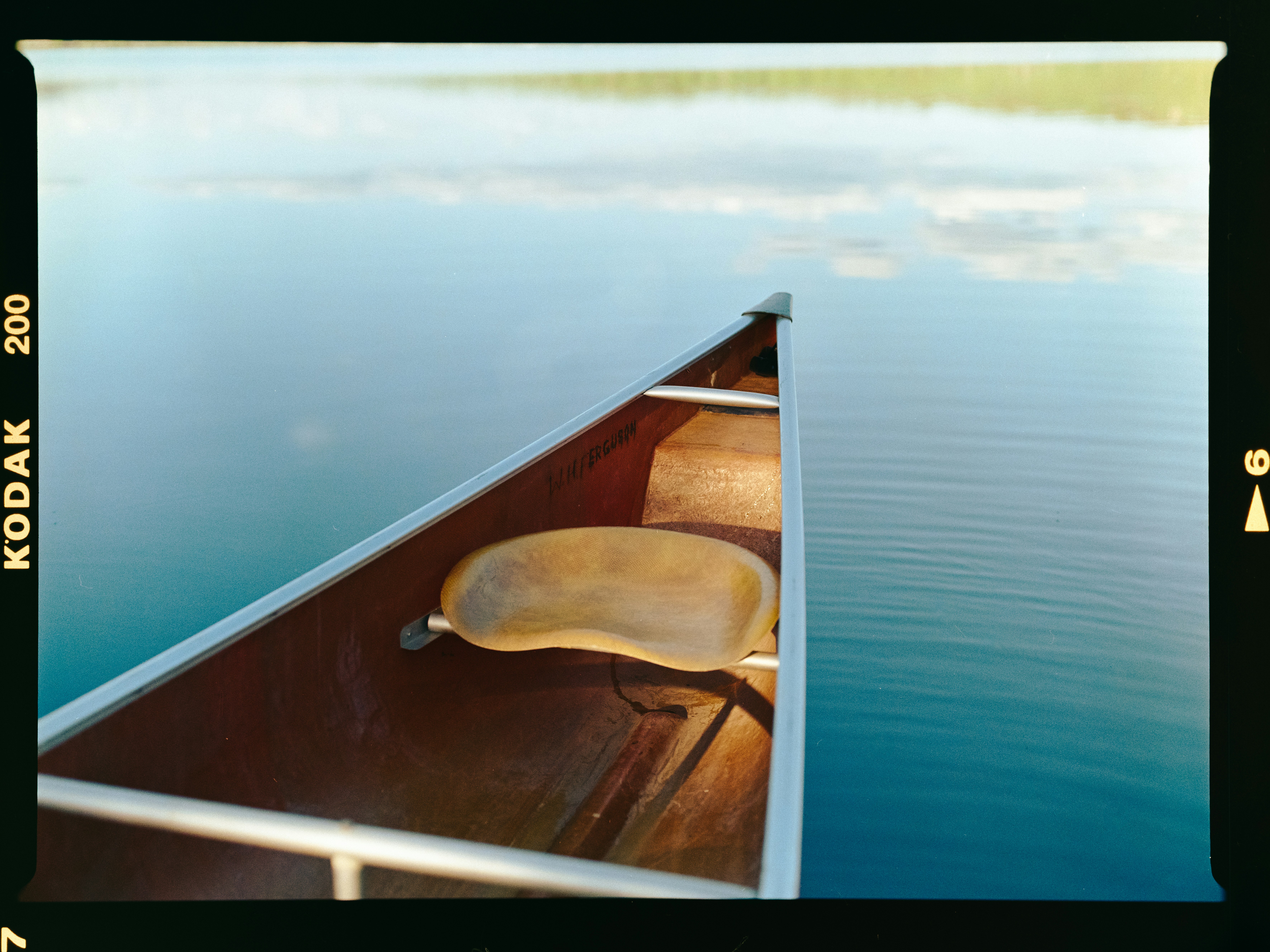 Empty canoe resting on tranquil lake water