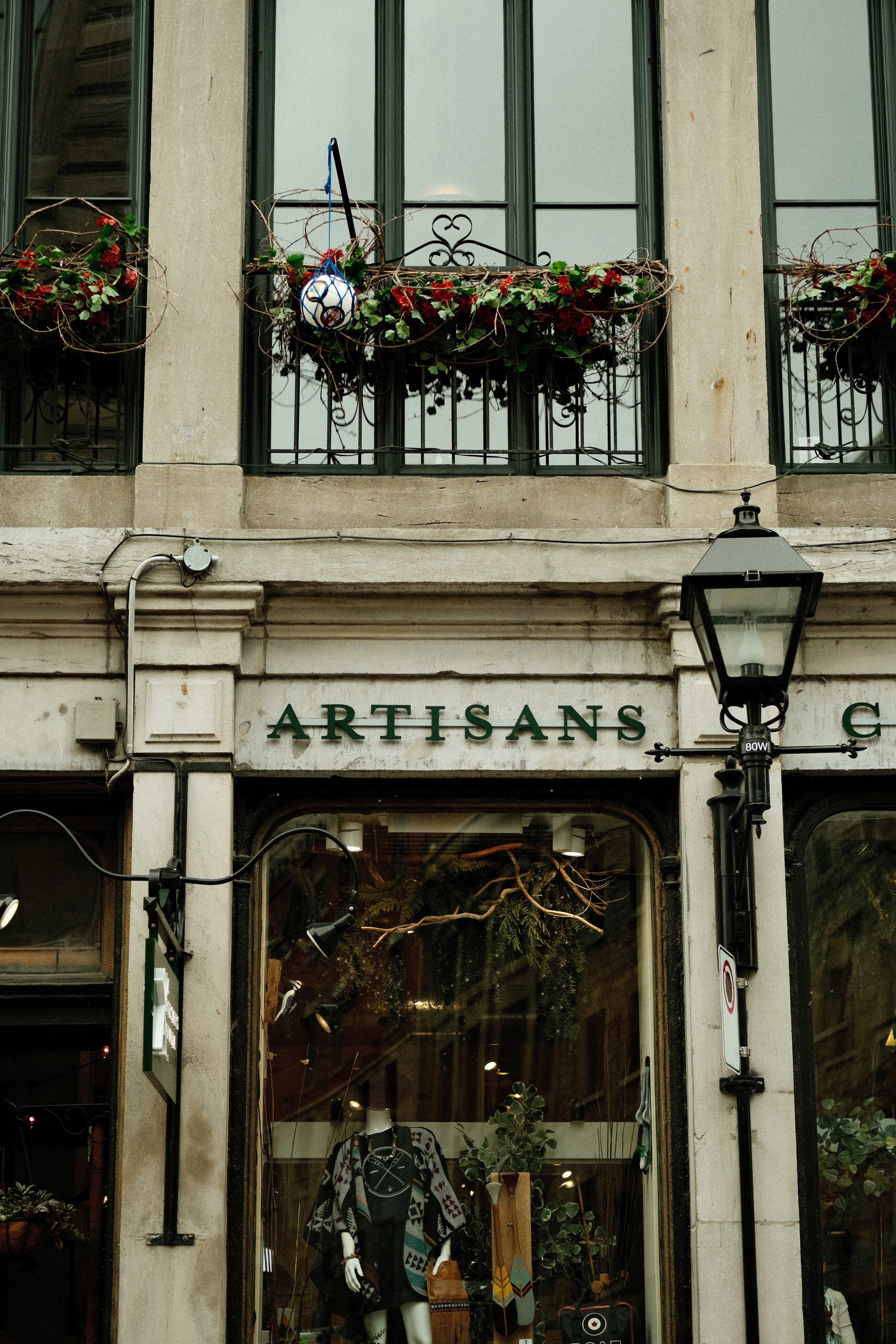 Boutique artisanale avec vitrine et jardinières à fleurs.