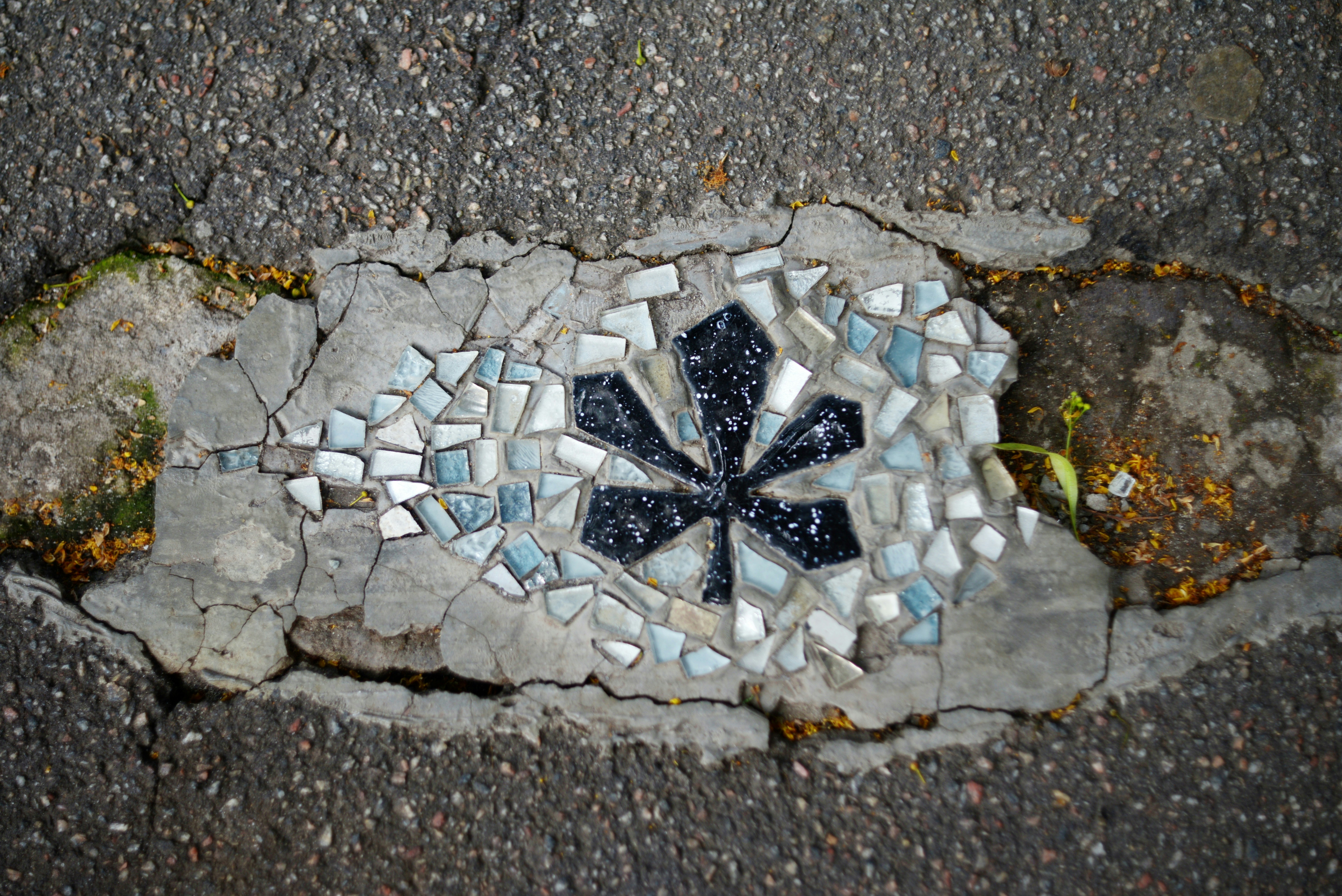 A mosaic star embedded in cracked asphalt.
