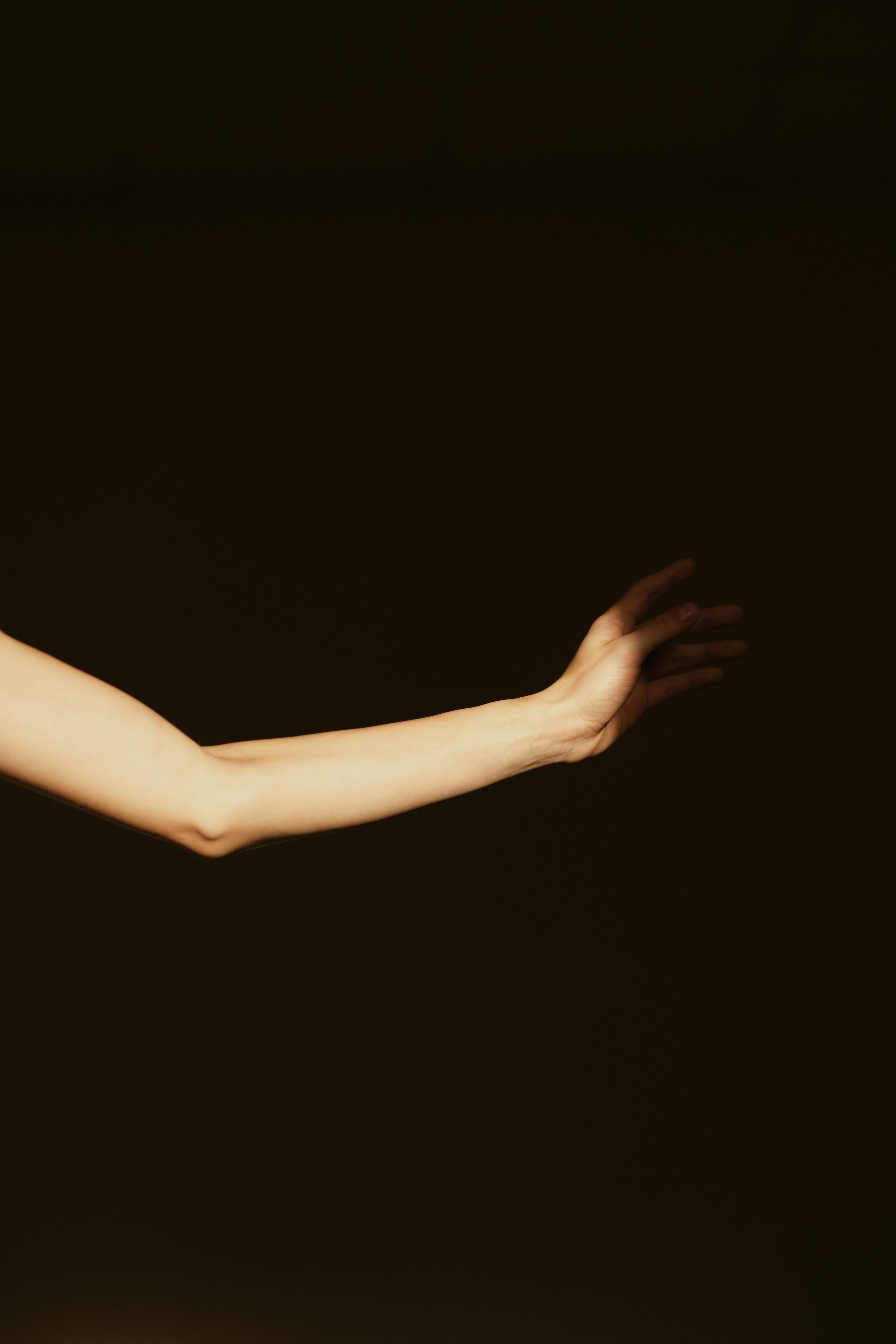 A person's arm and hand extended in a dark setting.