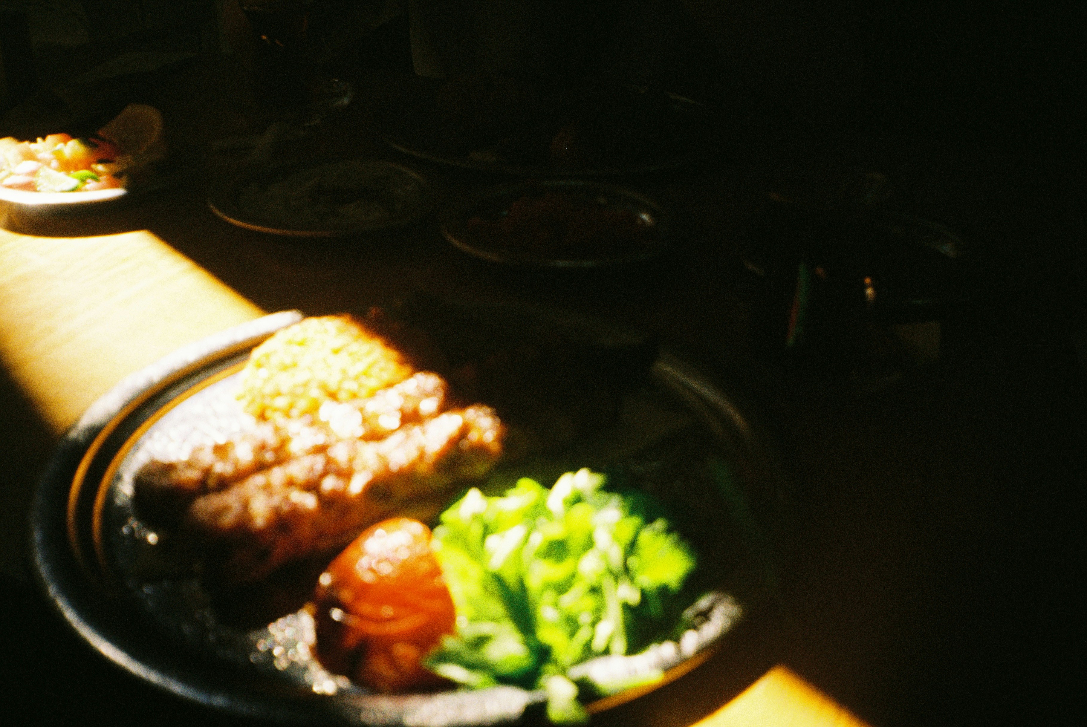 Food plate with sausages and greens illuminated by sunlight.