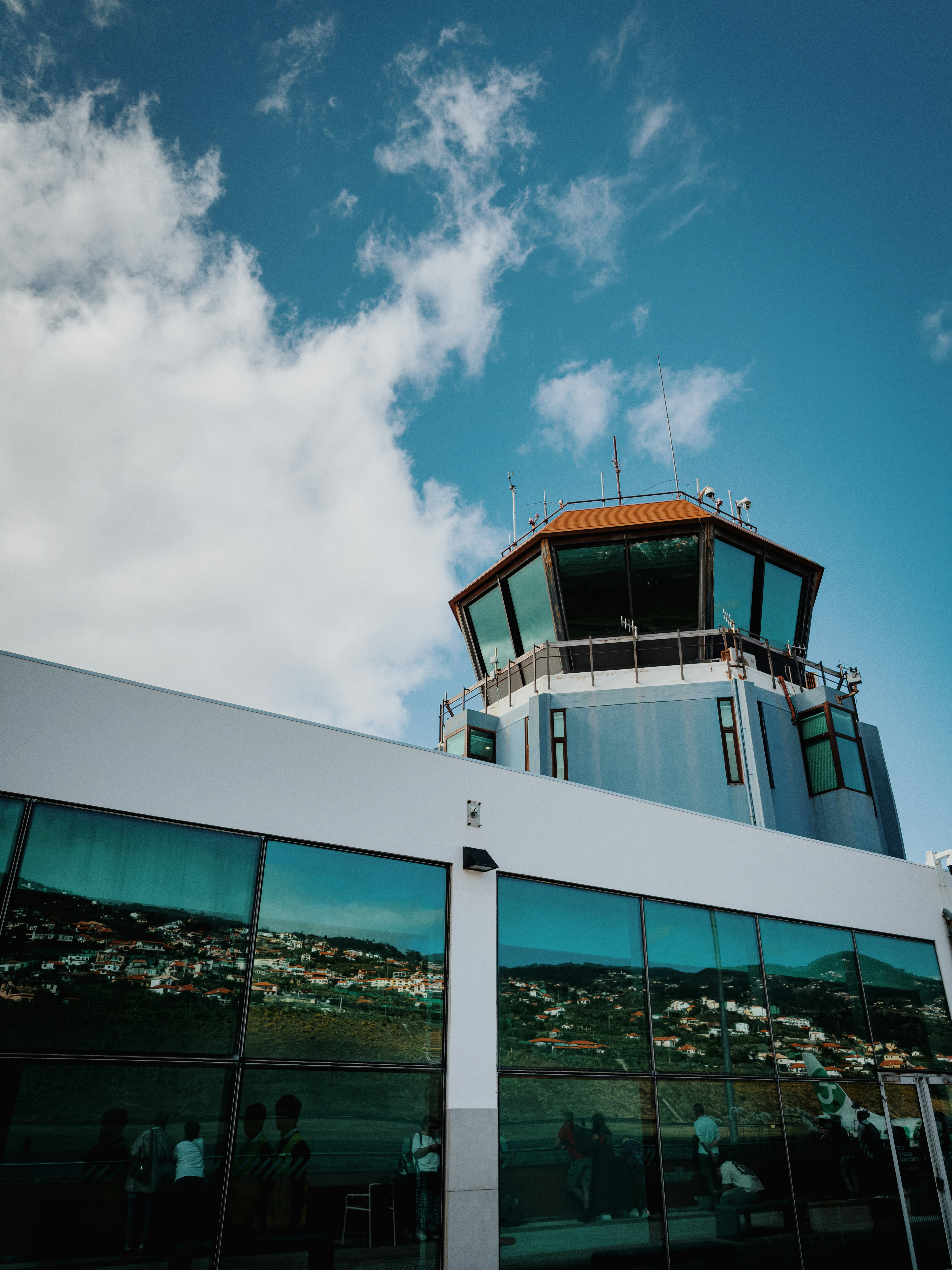 Airport control tower and terminal building under blue sky.