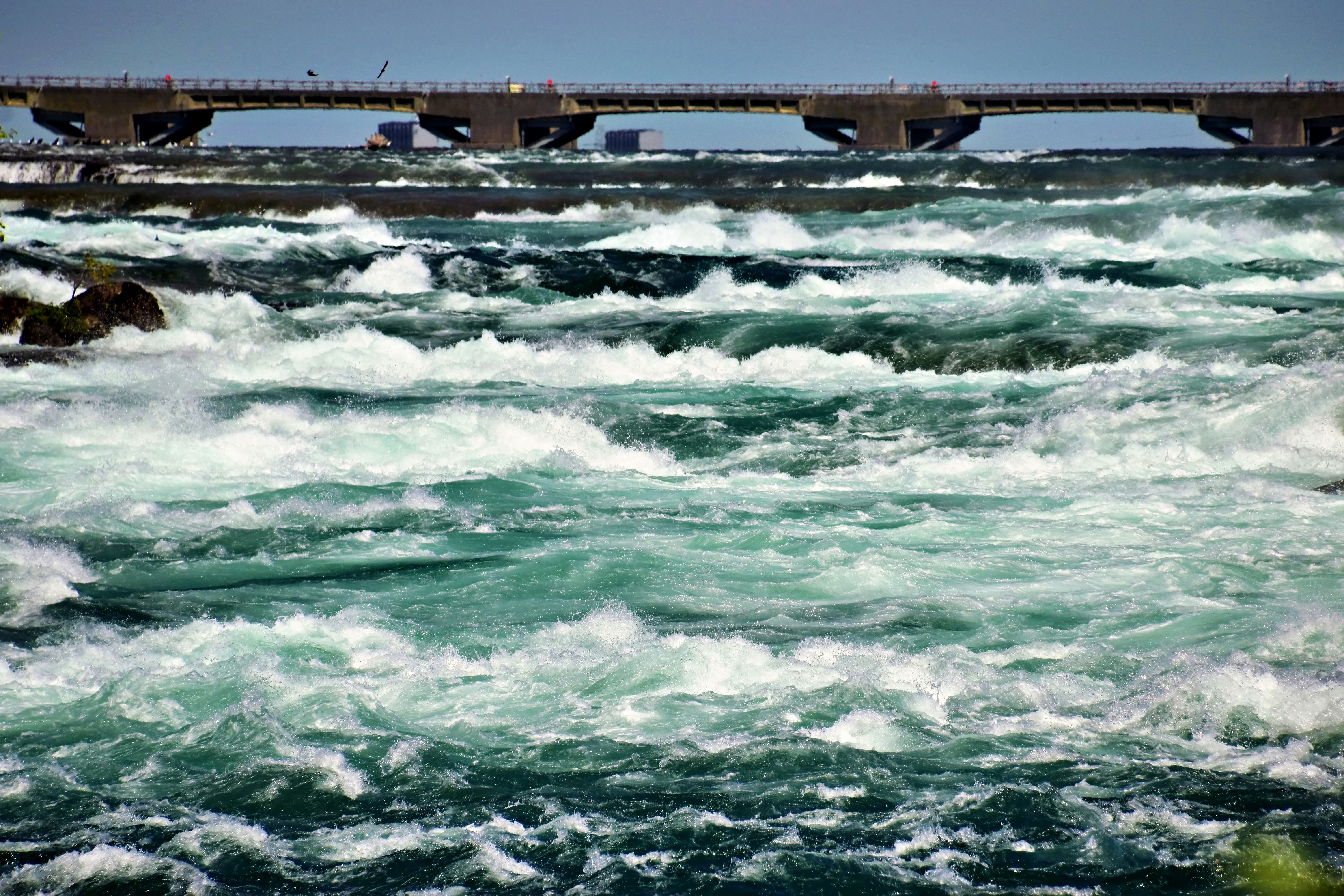 Turbulent river water with a bridge in the background