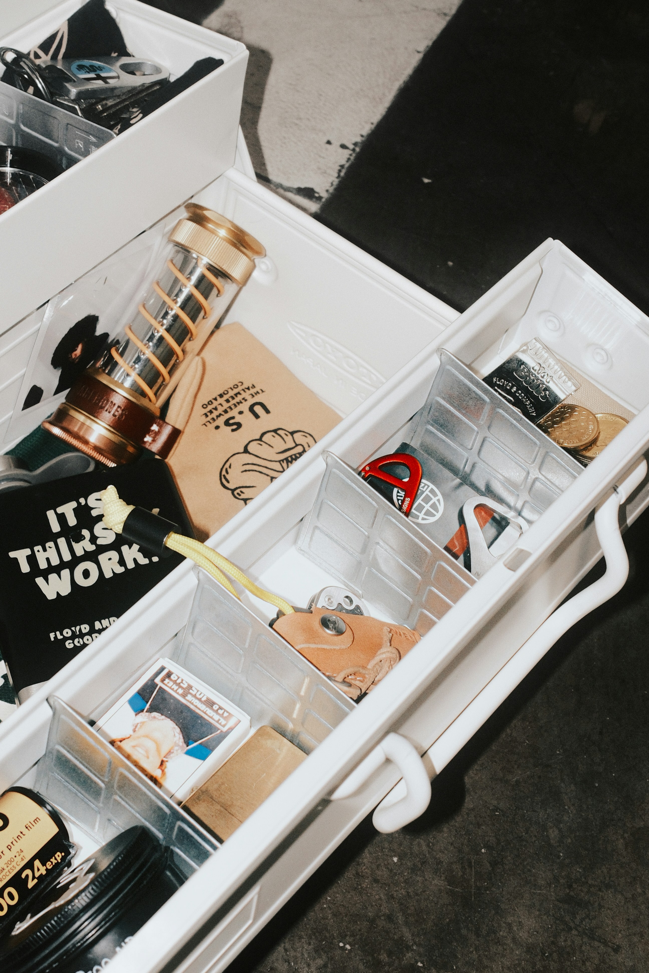 White storage box filled with tools, bottles, and miscellaneous items.