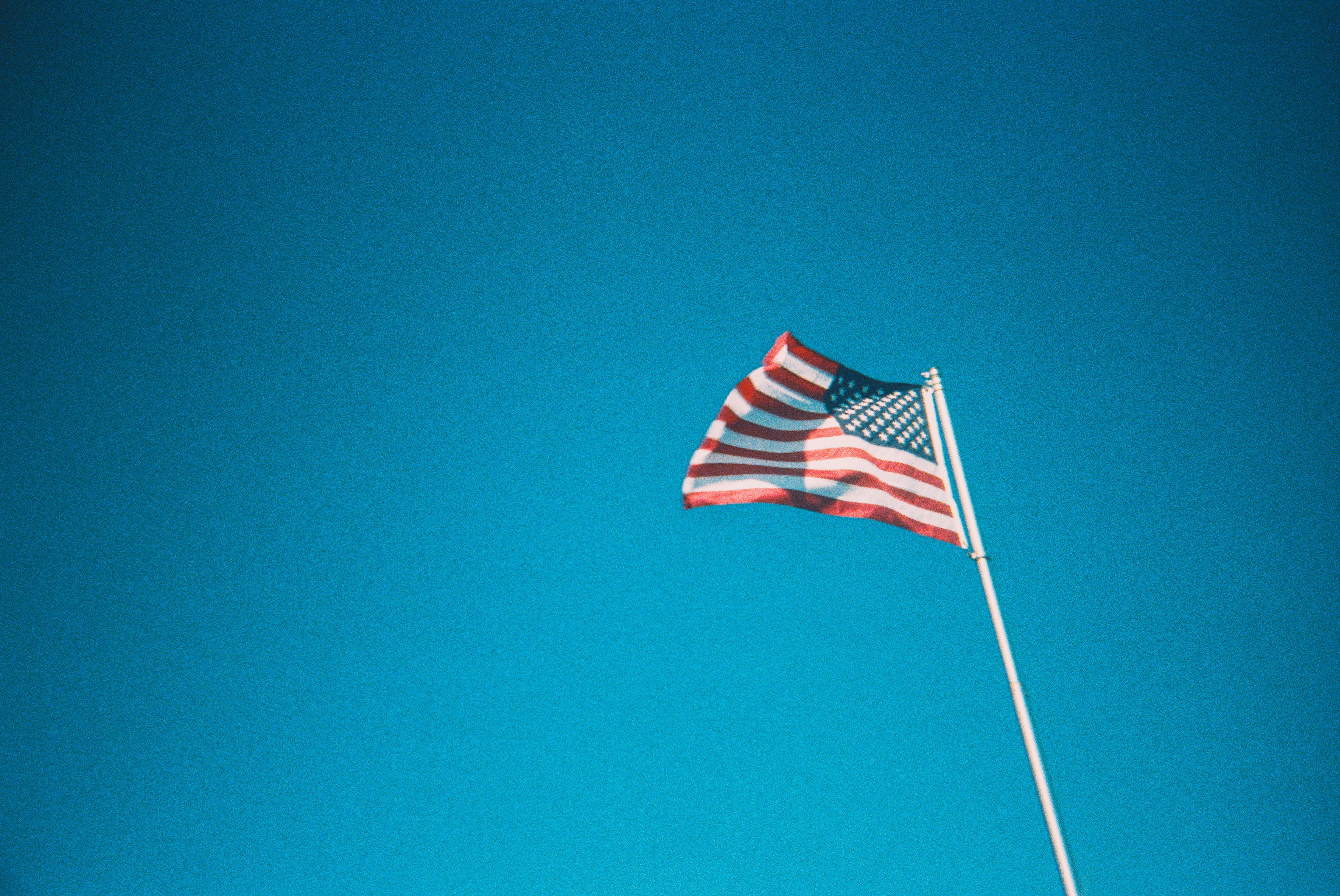 An american flag waving against a bright blue sky.