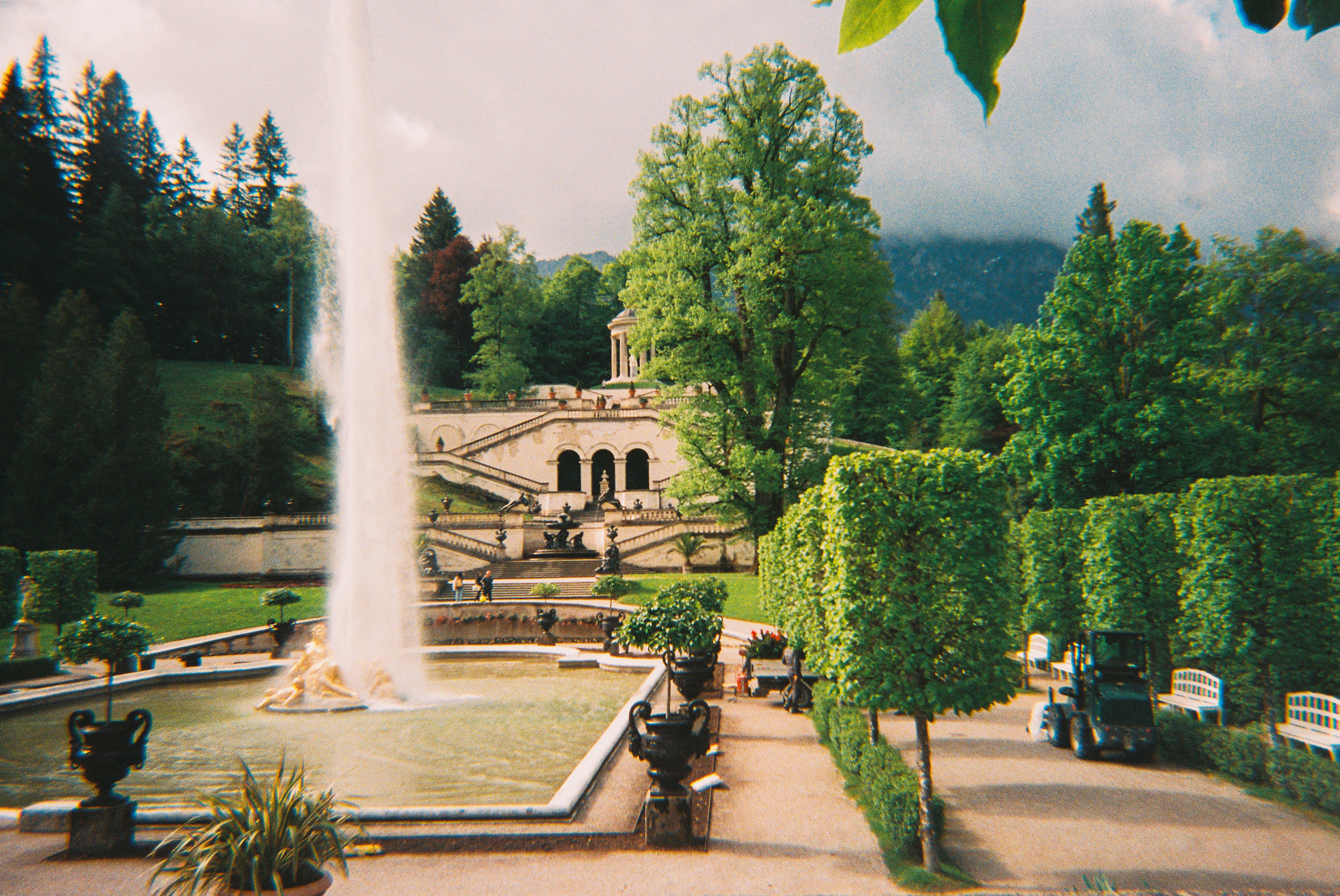 A grand garden with a tall fountain and terraced landscaping.
