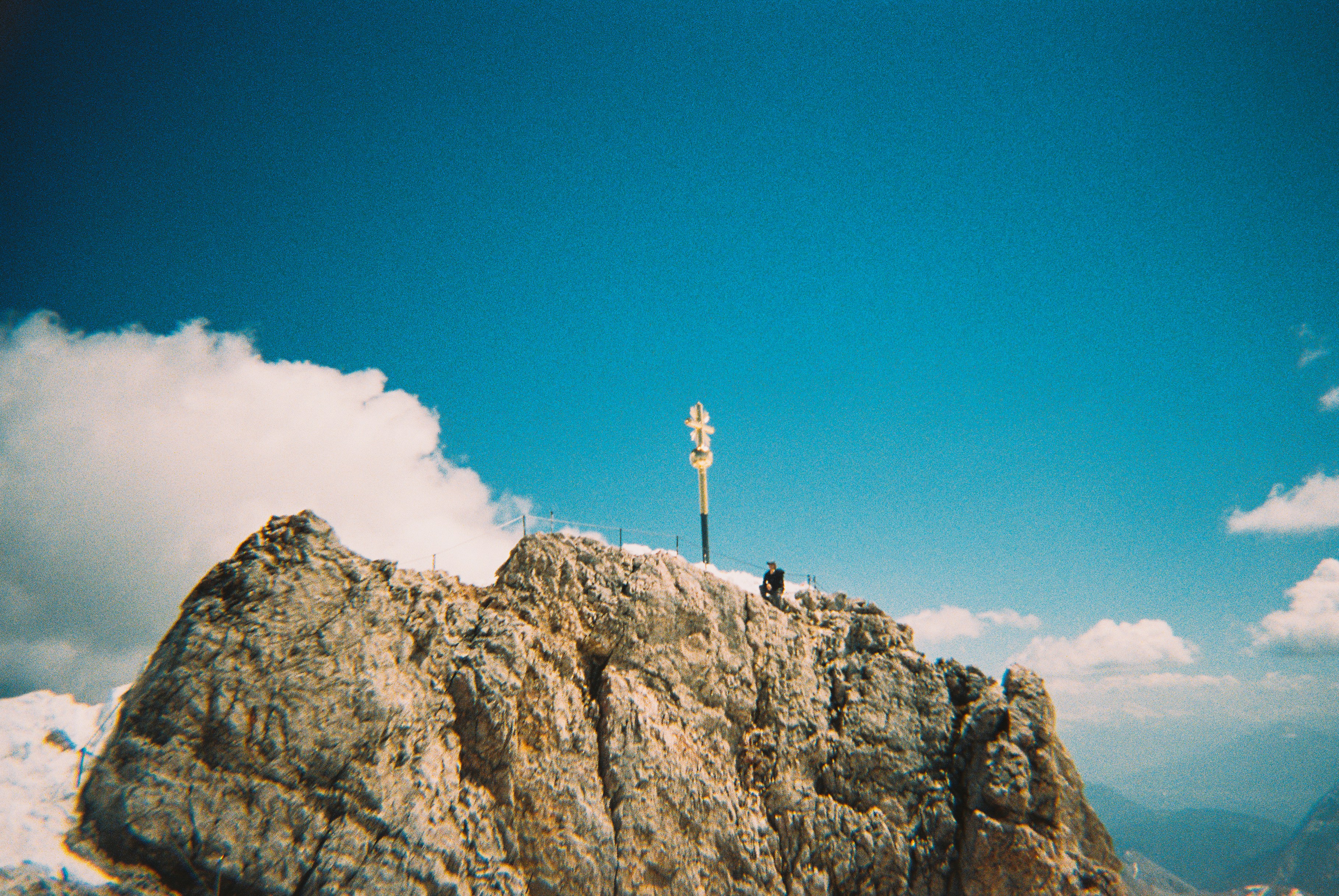 Rugged mountain peak with a signpost and person.