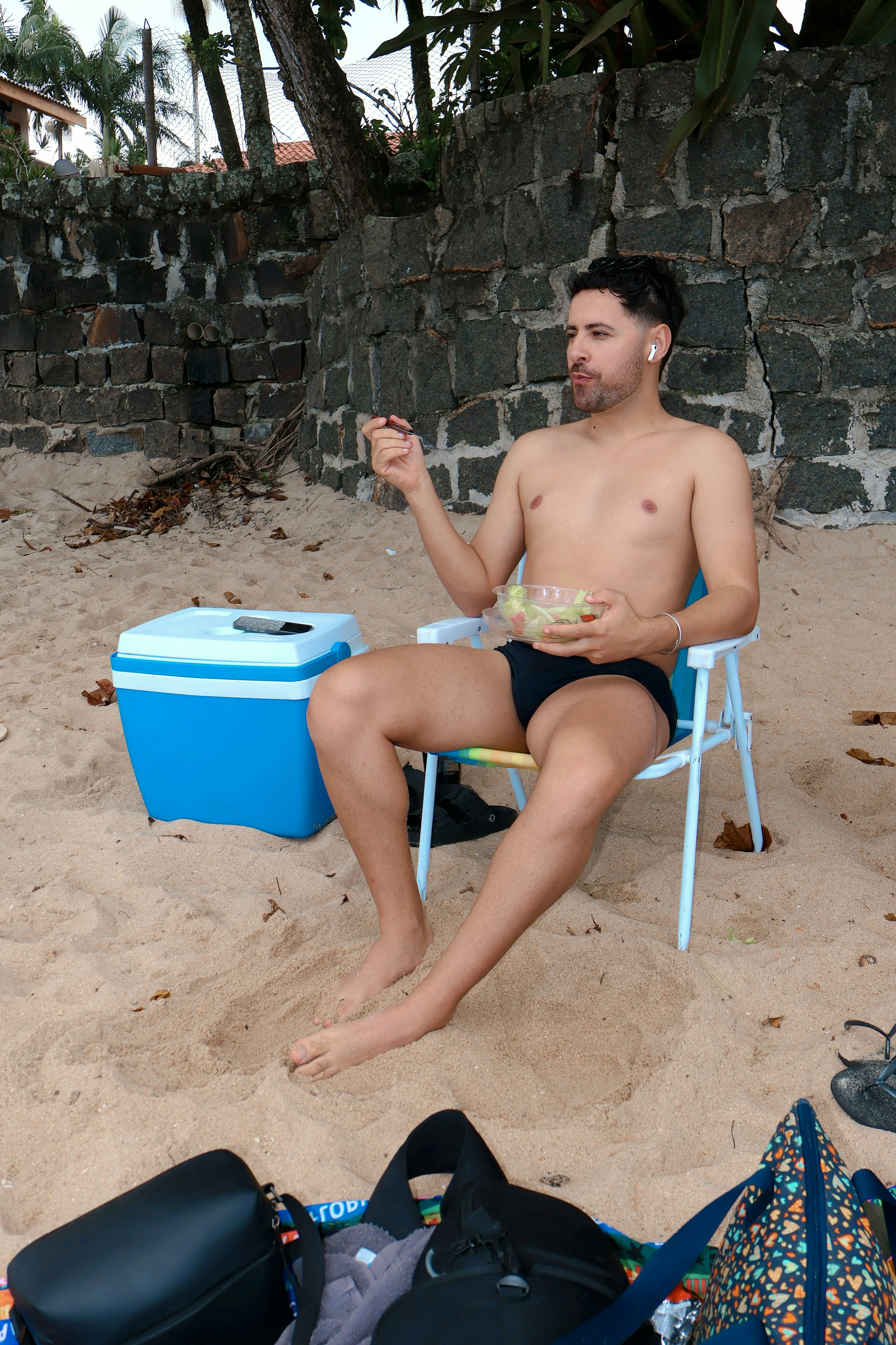 Man eating from a bowl on a beach chair.