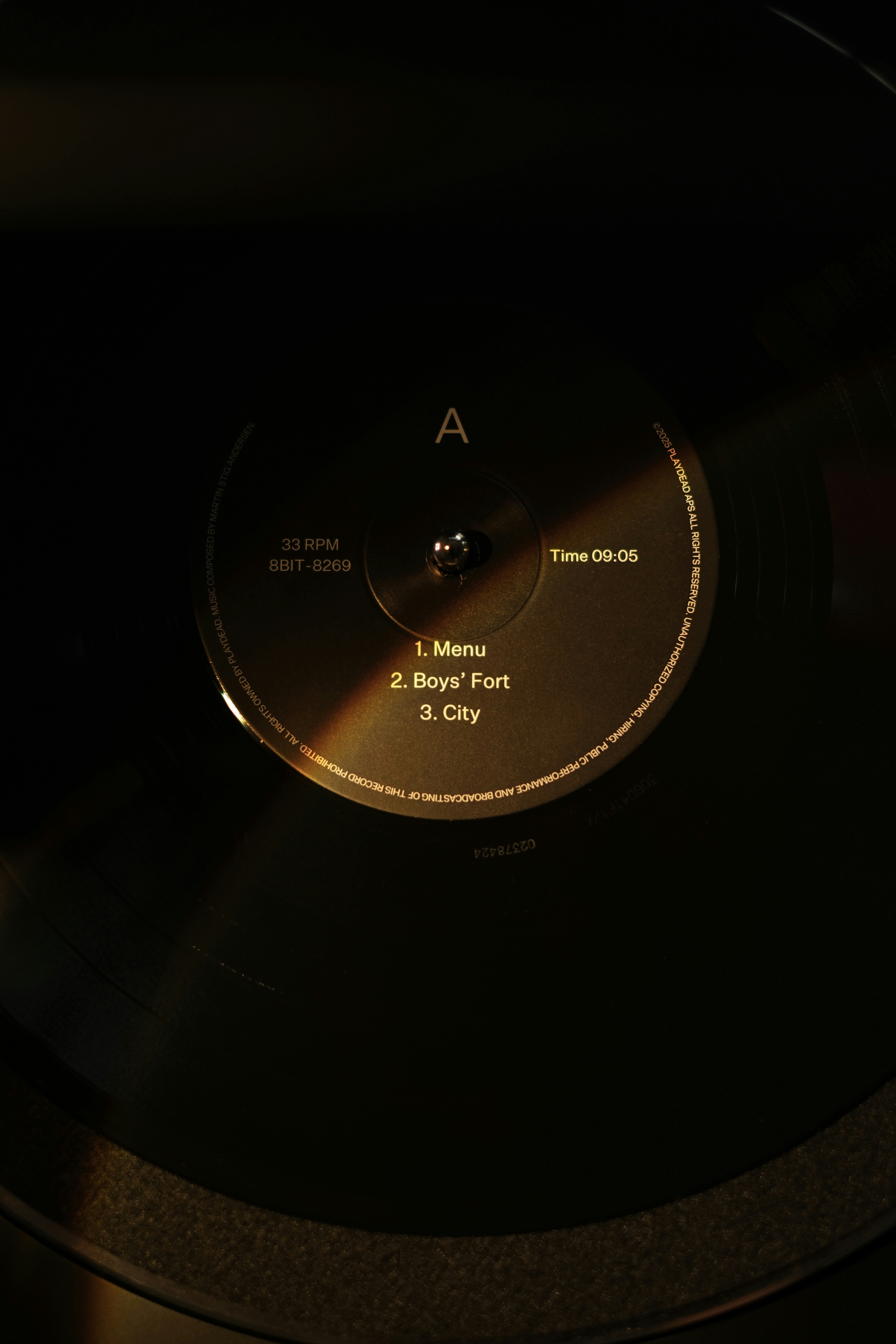 A vinyl record spinning on a turntable in low light.