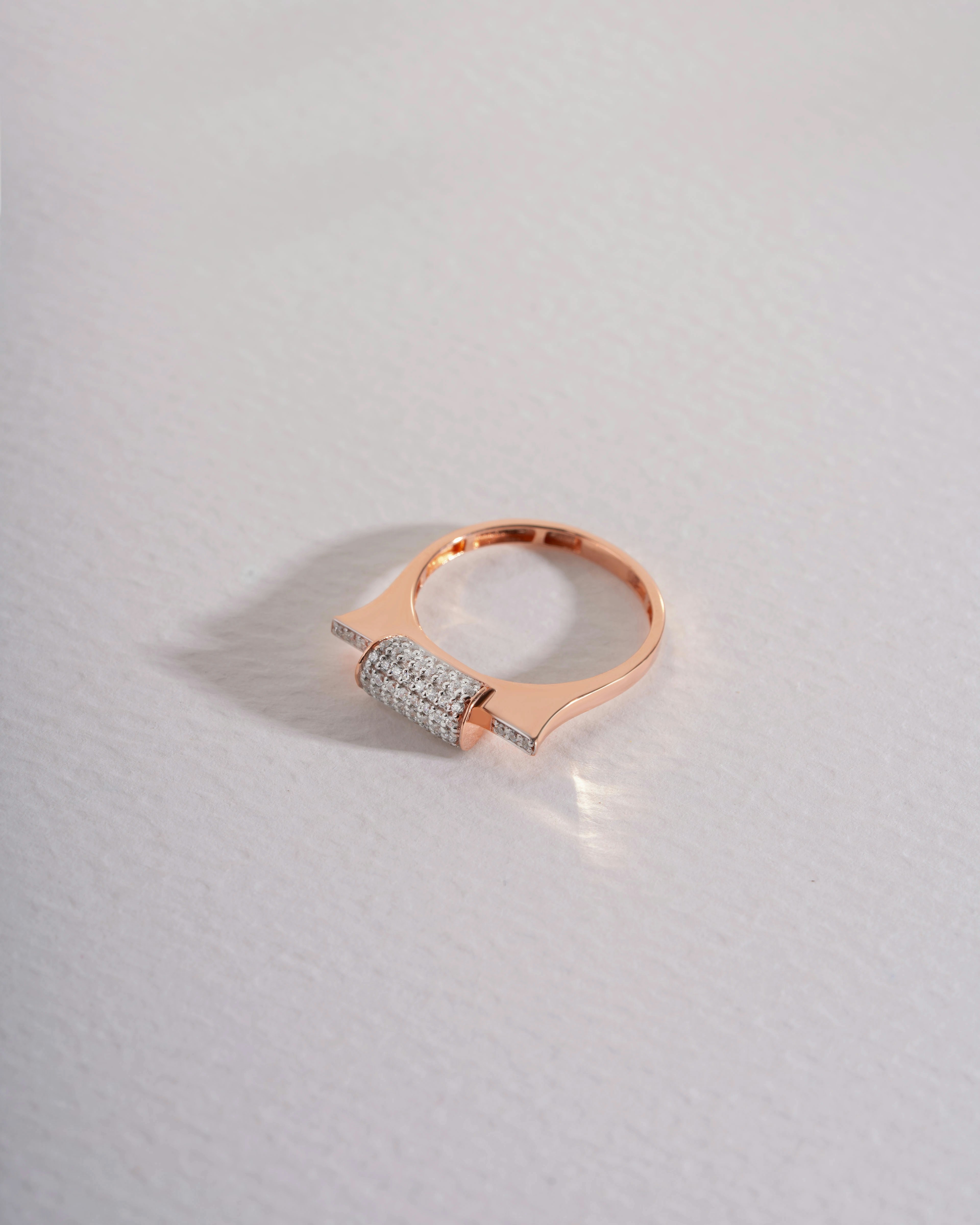A rose gold ring with a diamond-studded rectangular design.