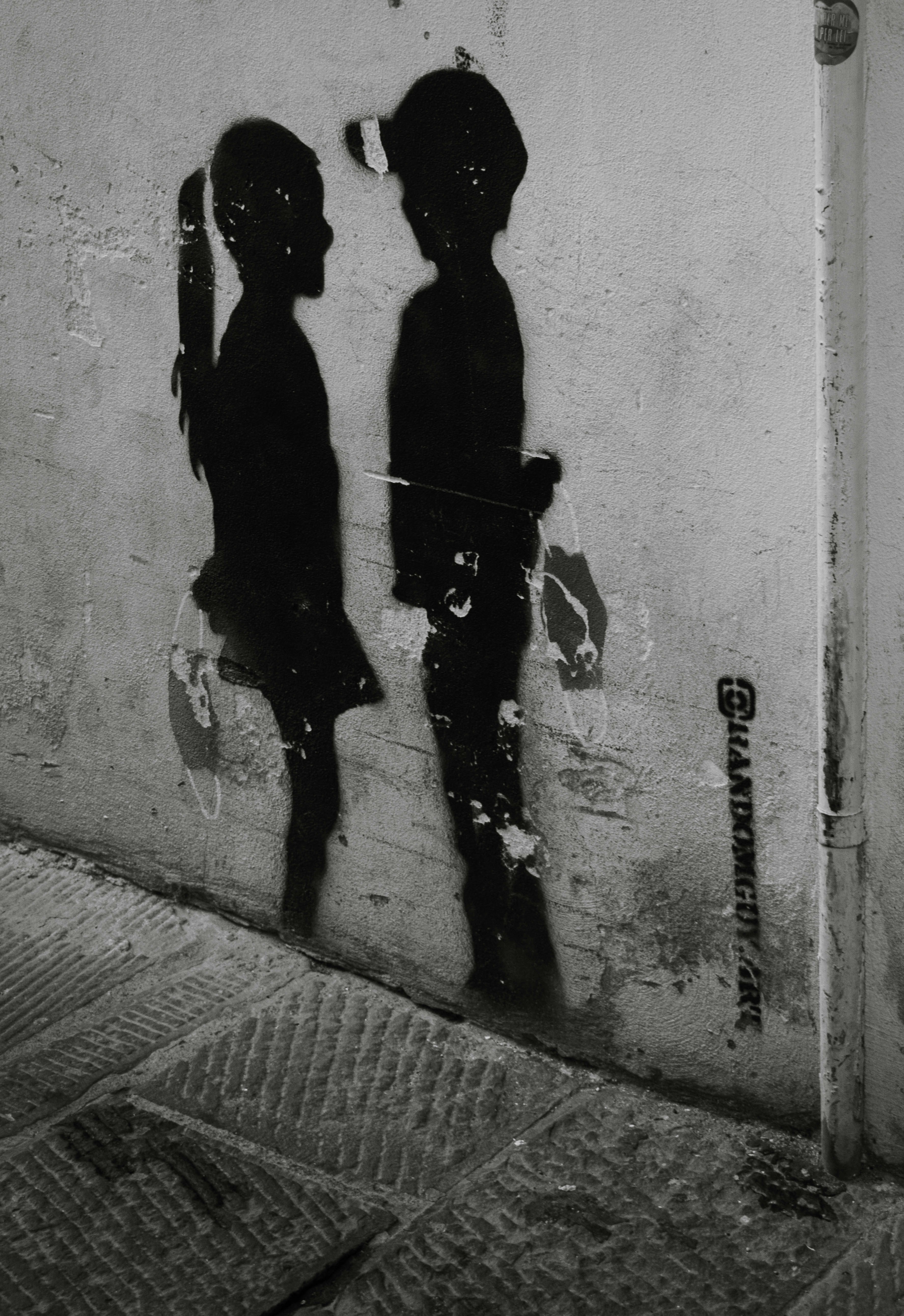 Black stencil graffiti of two children on a wall