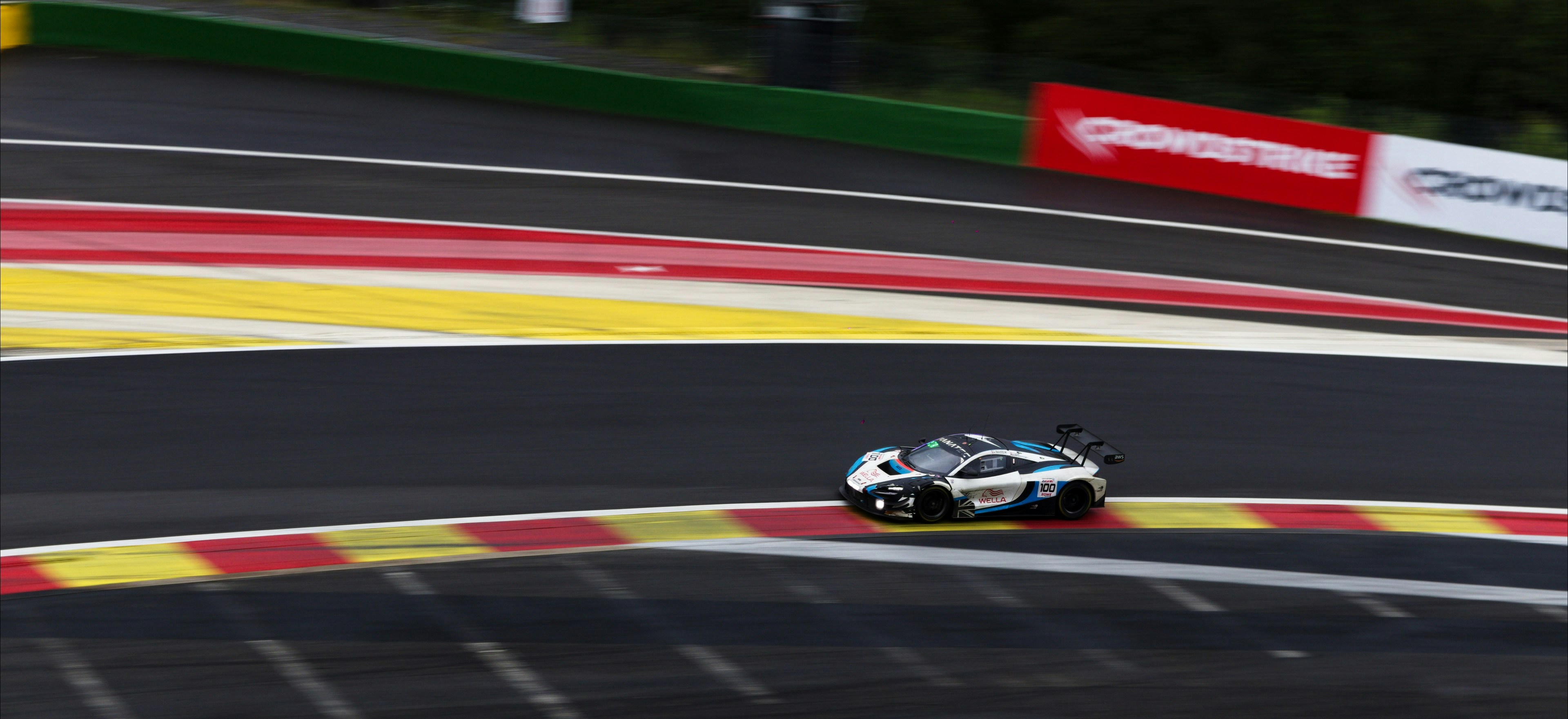White race car on a track with colorful curbs