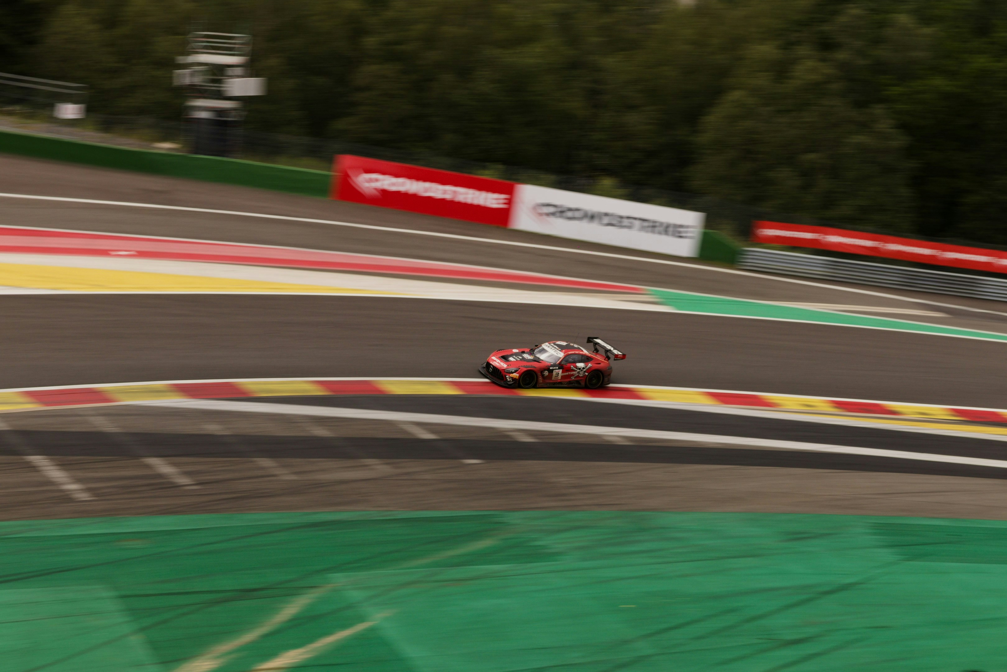 A red race car speeds on a colorful track