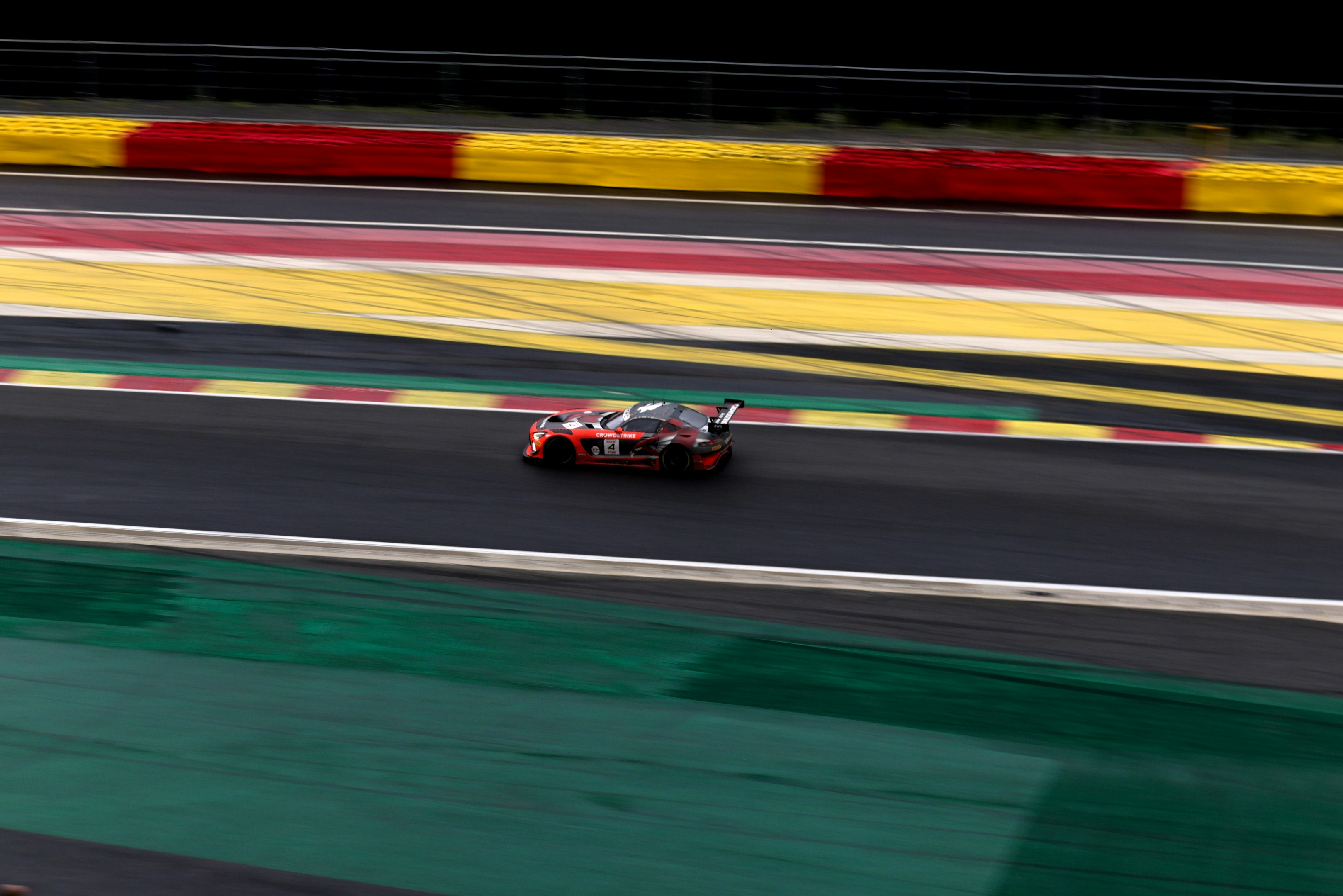 A red and black race car speeds on a track