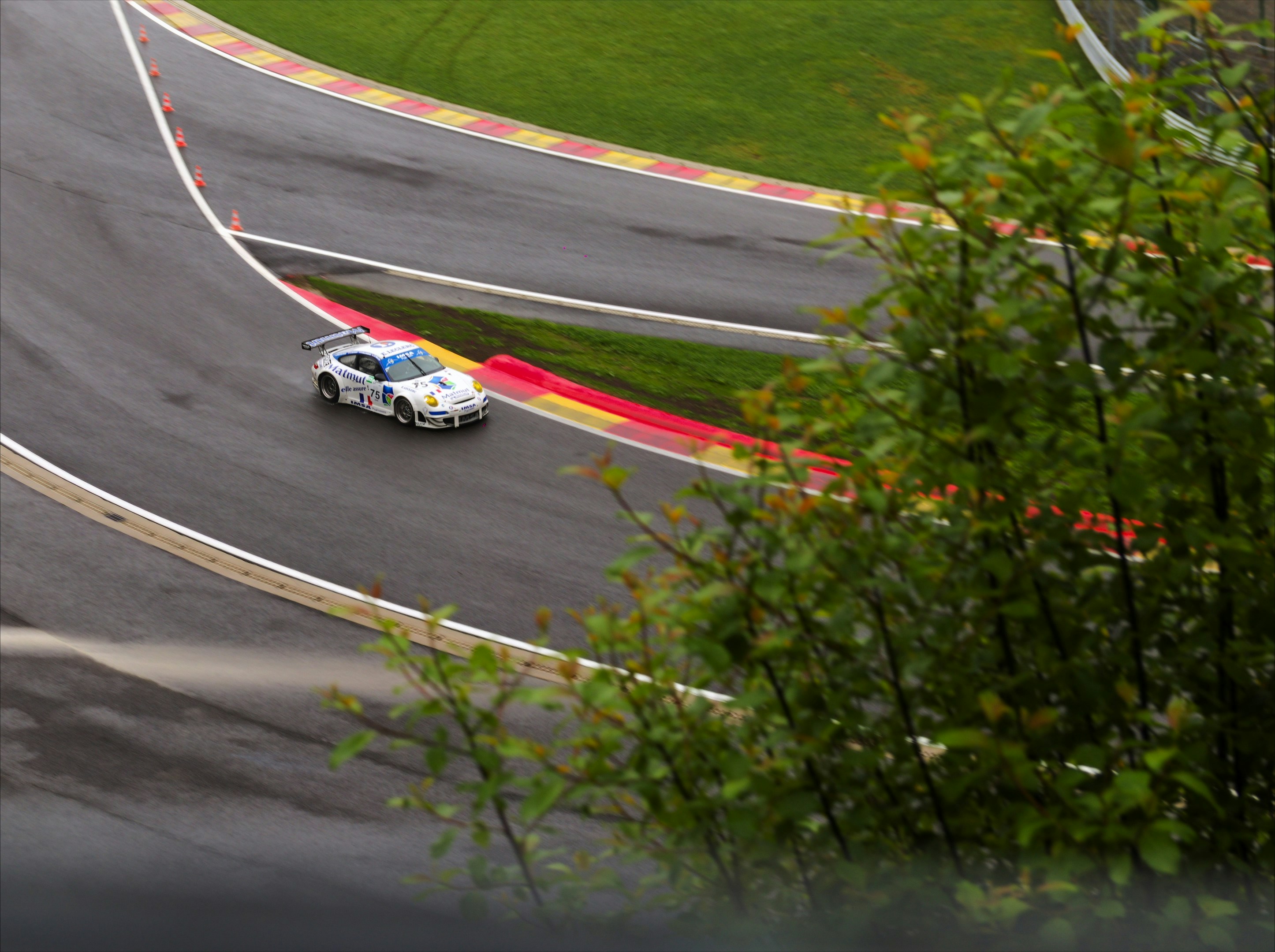 A white race car speeds on a winding track
