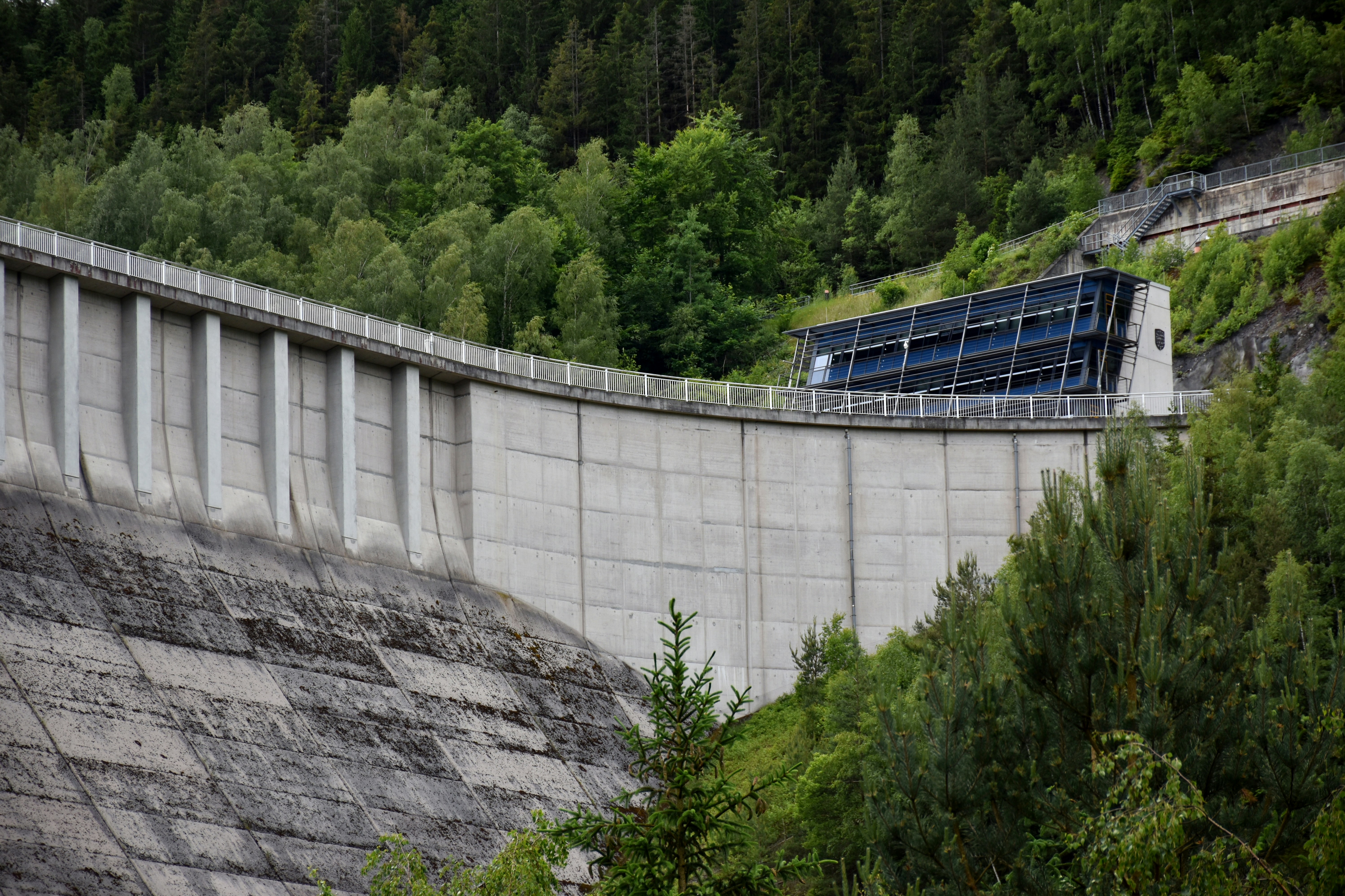 Uma enorme represa de concreto cercada por uma floresta verdejante e exuberante.
