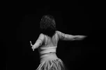 Back view of a dancer in a fringed skirt.