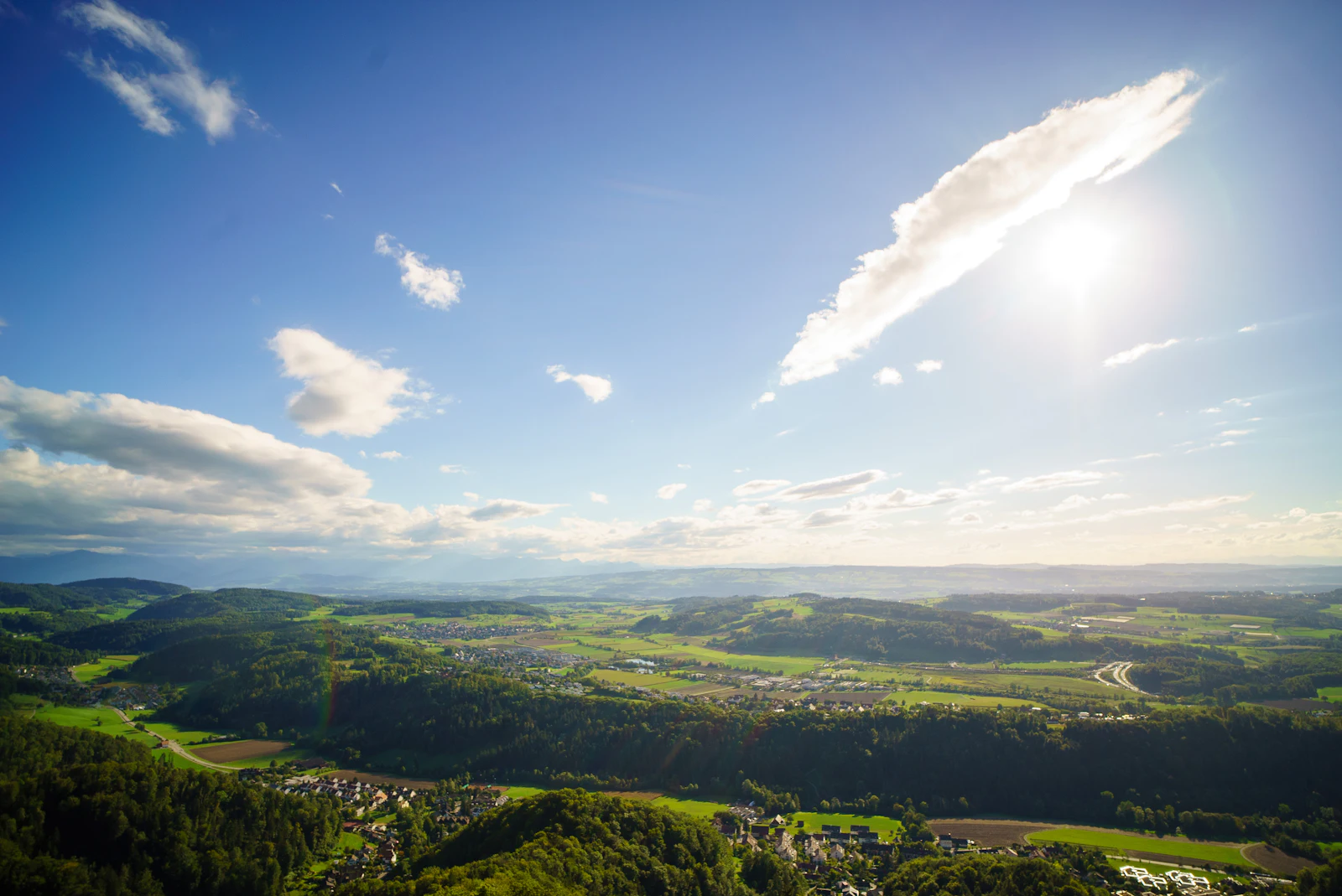 Sun over a wide stretch of green hills.