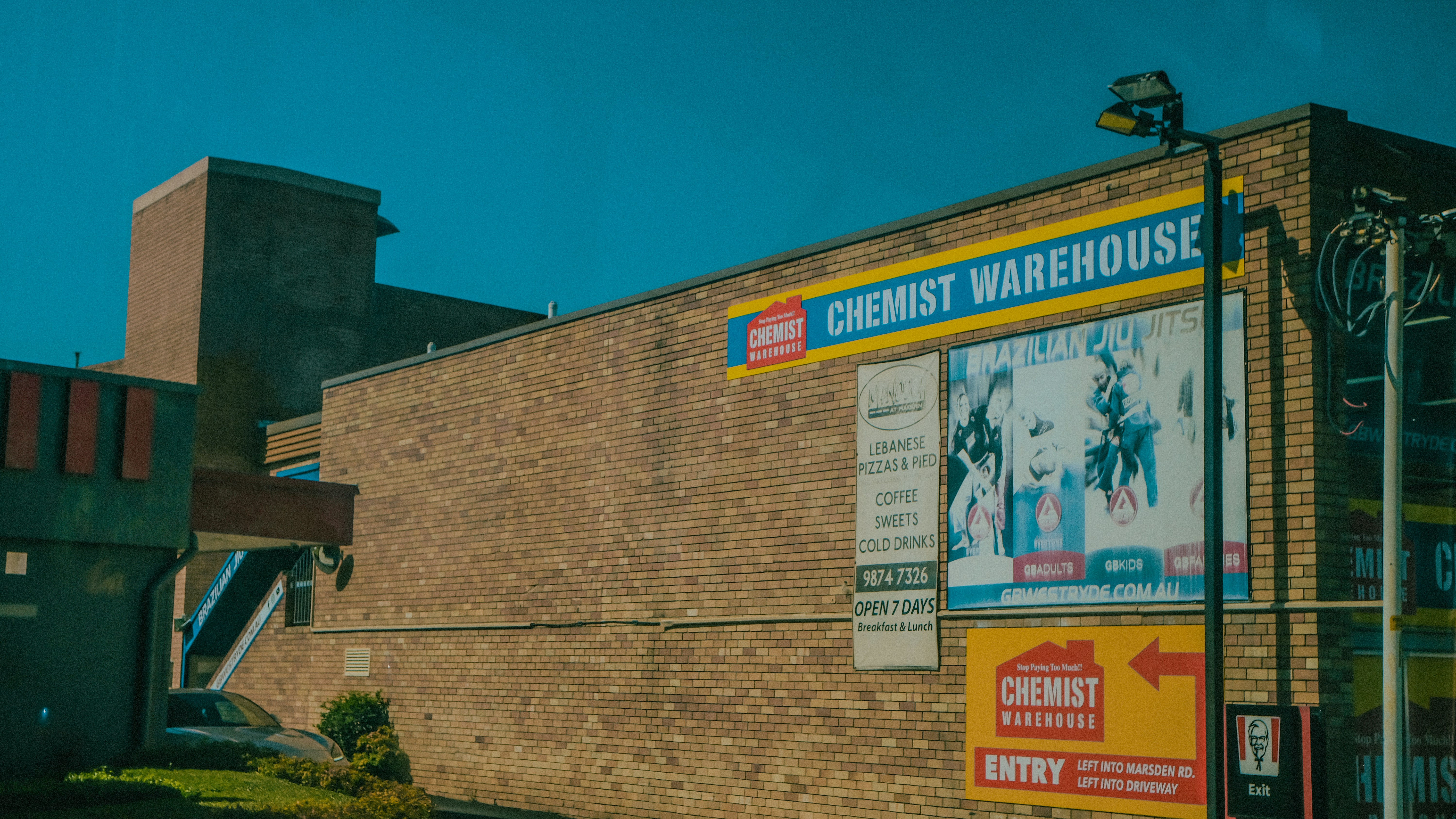 A brick building with a chemist warehouse sign and advertisements.