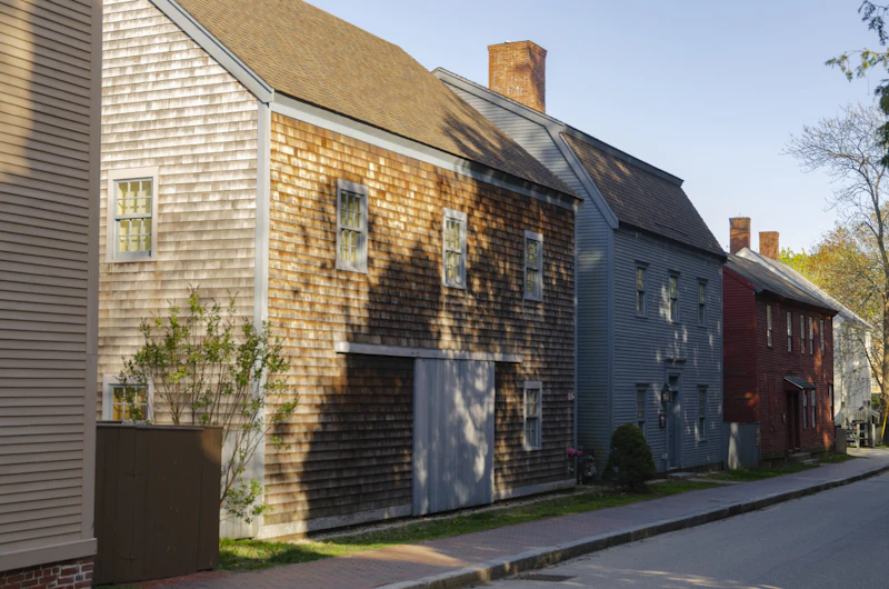 A row of historic shingled and clapboard houses along a quiet street