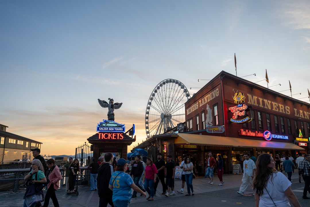 Lively pier with ferris wheel and people at sunset.