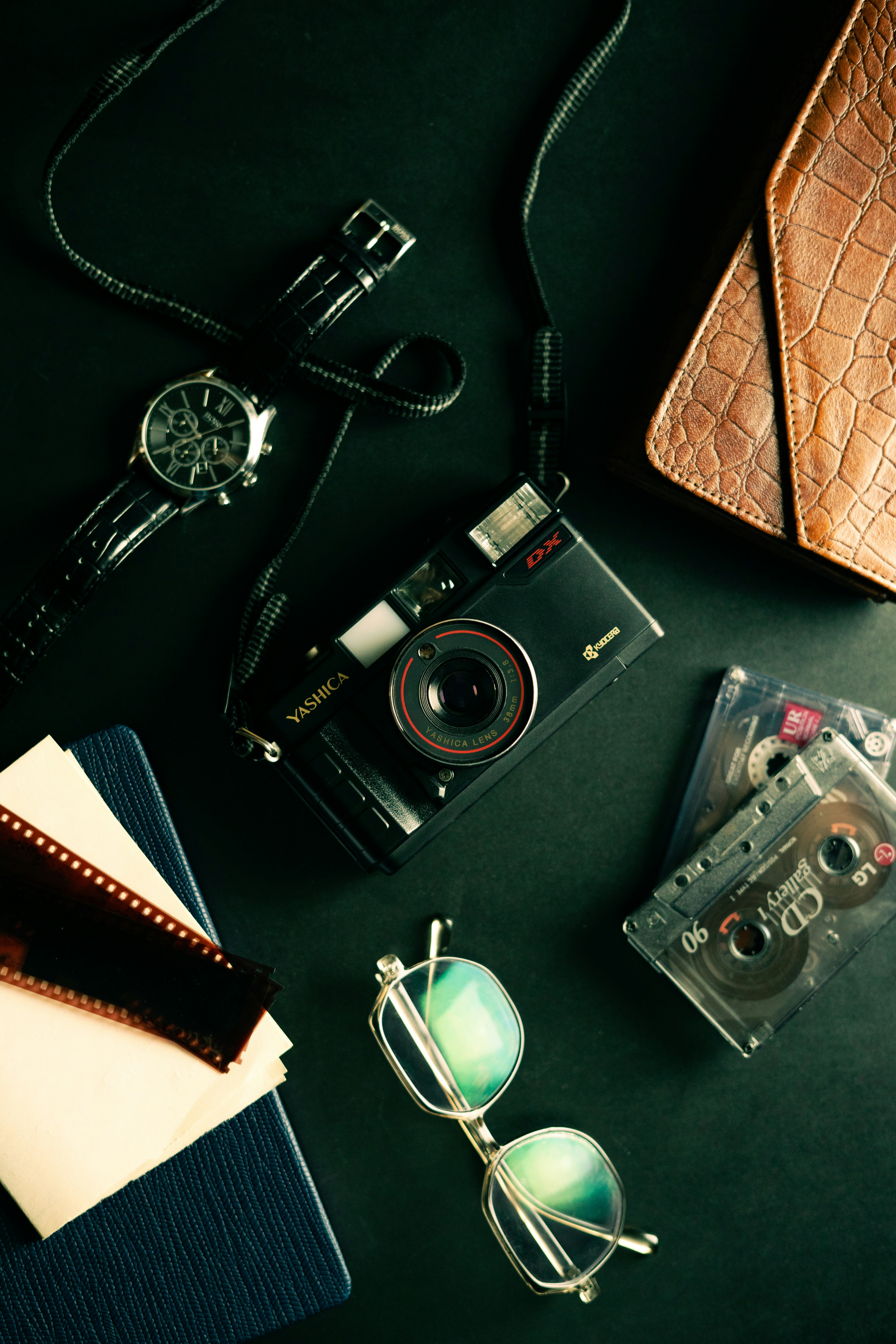 Flat lay of vintage camera, watch, glasses, film, and cassettes