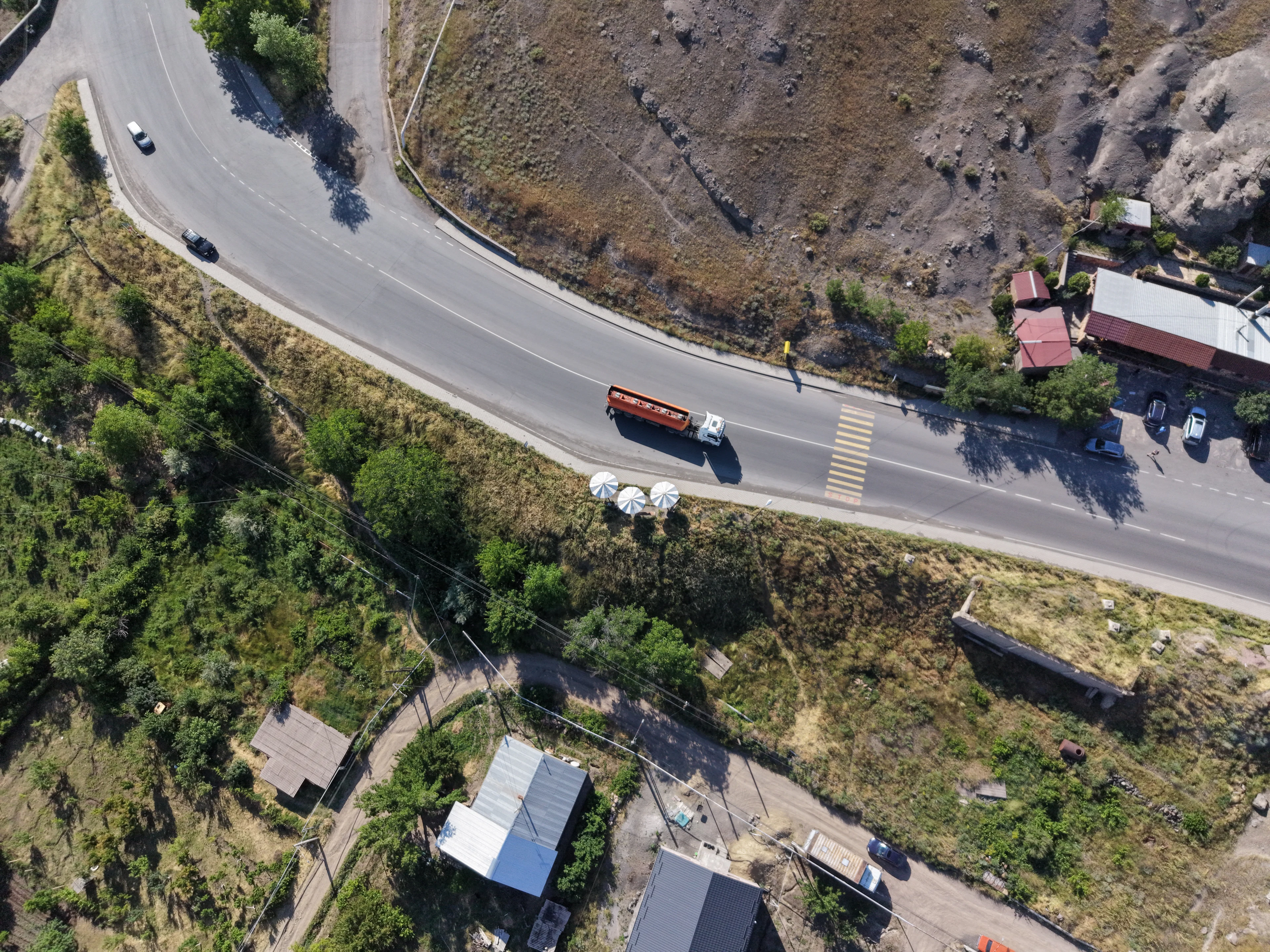 Aerial view of a highway curving through hills with trucks on it