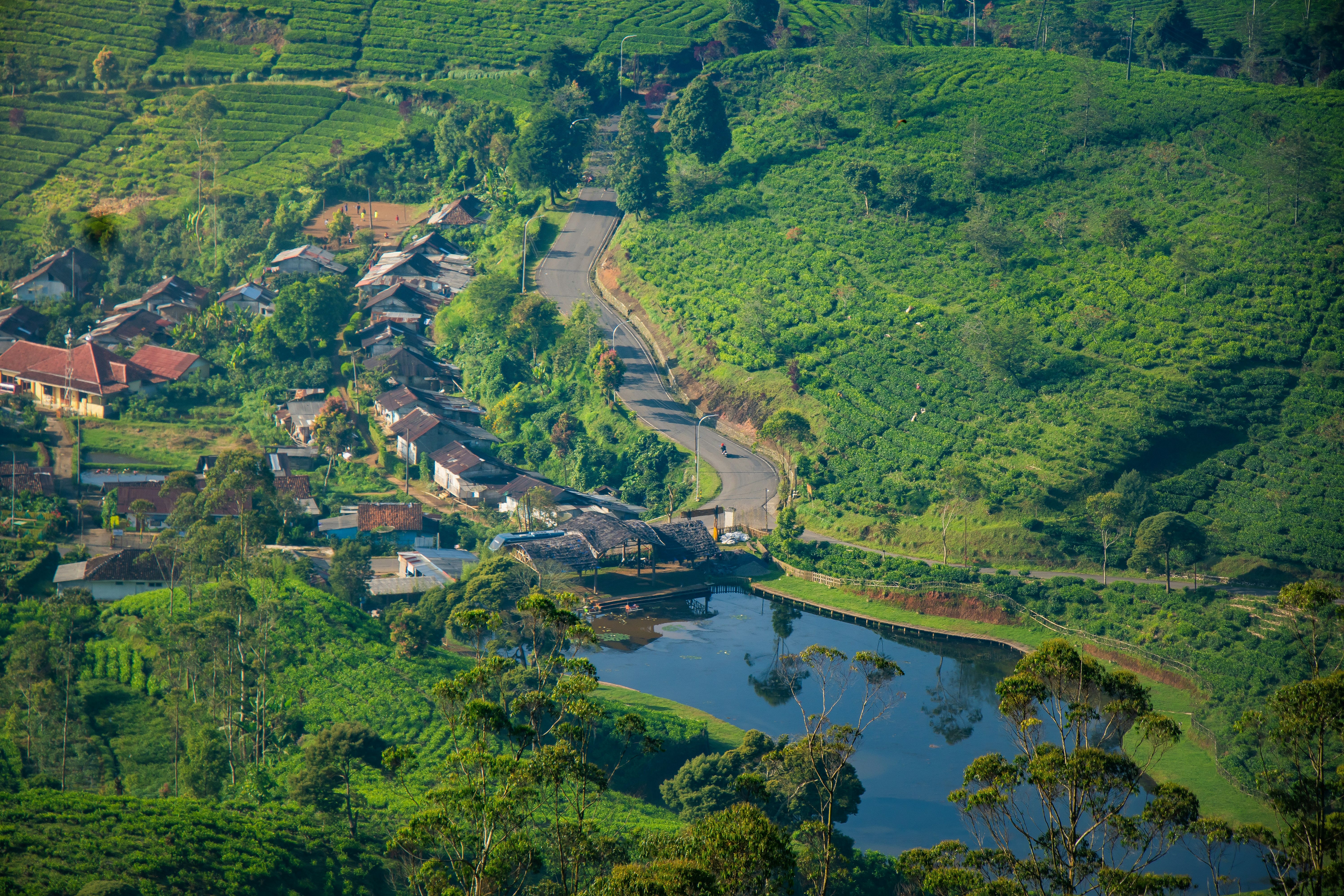 A village, winding road, and lake nestled among green hills.
