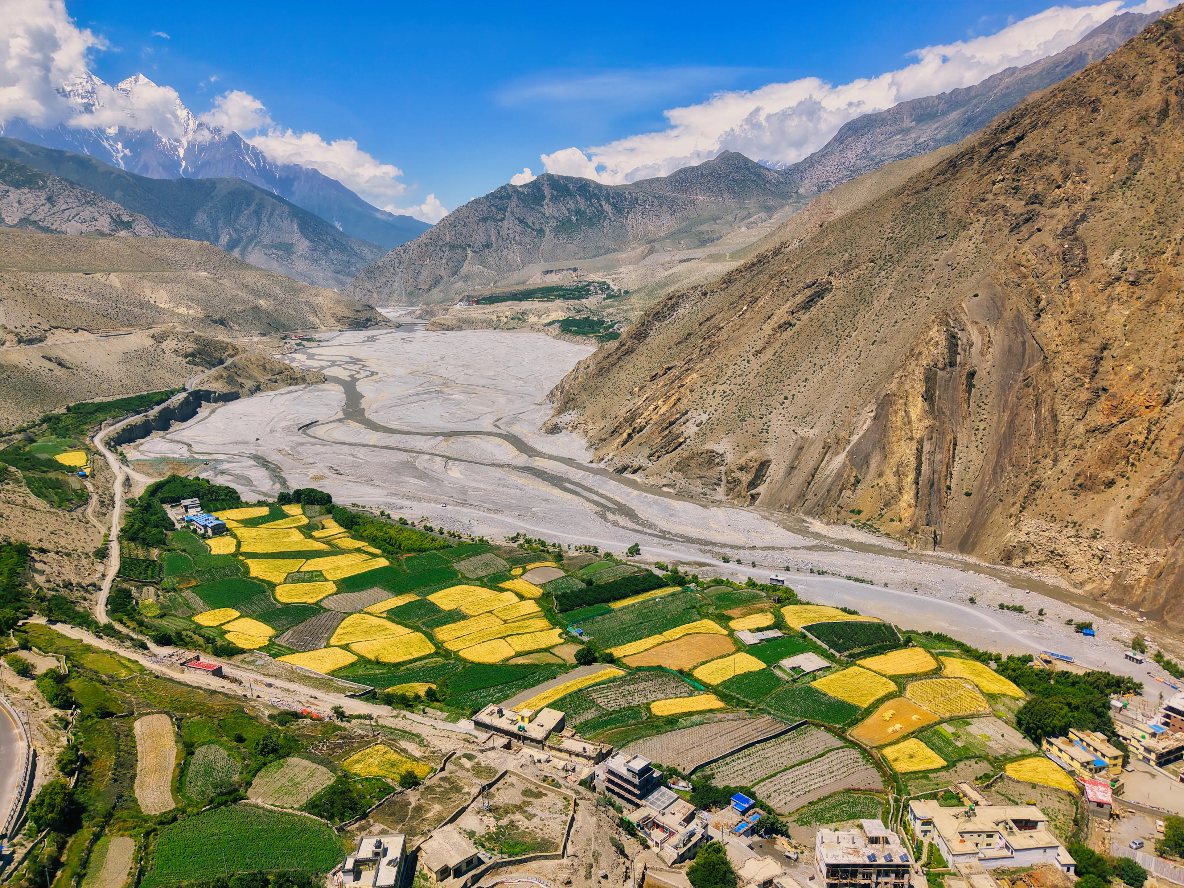 Cultivated fields beside a wide river in a mountain valley