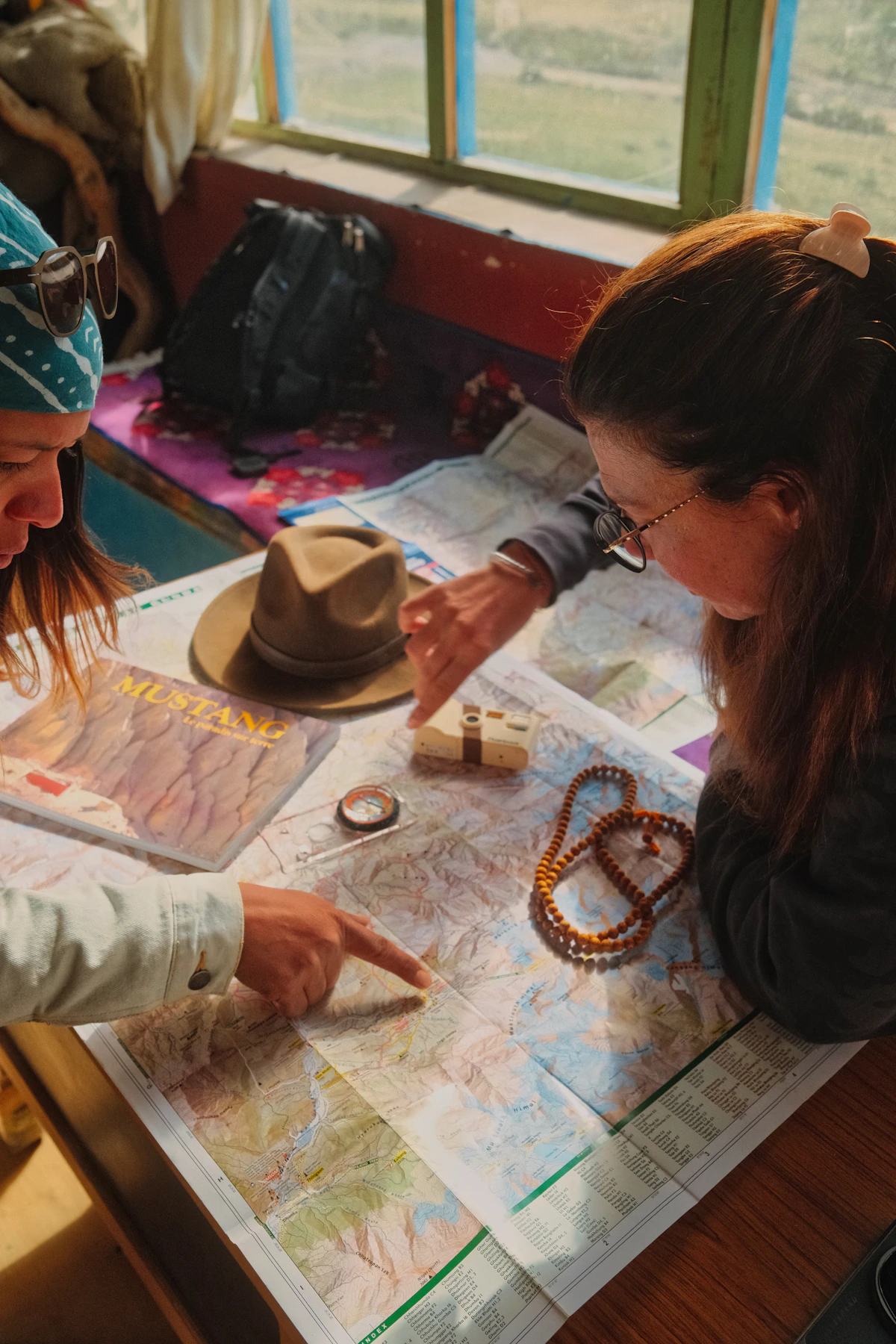 Two women planning a journey pointing at a detailed map