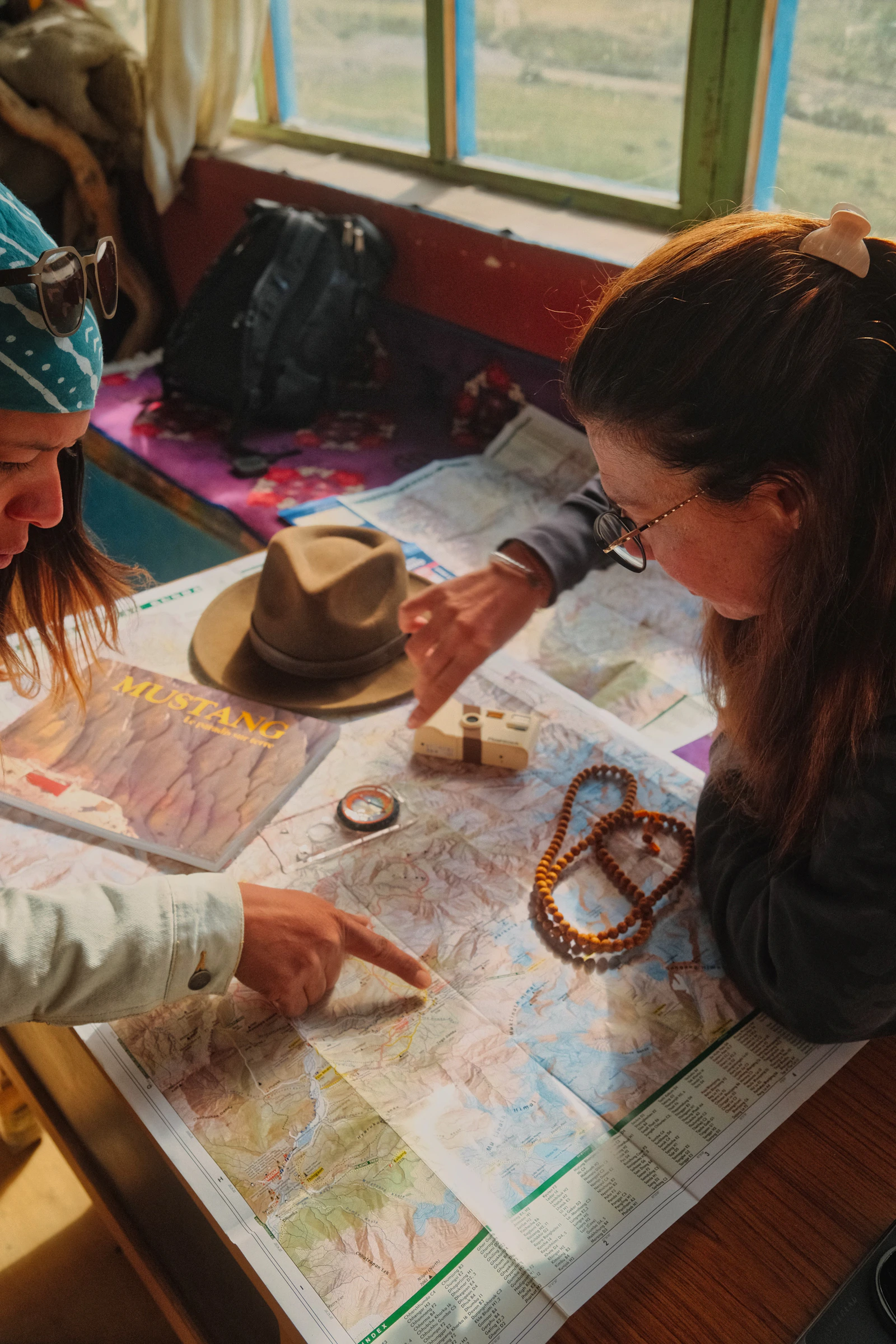 Two travelers pointing at a detailed paper map while planning a journey