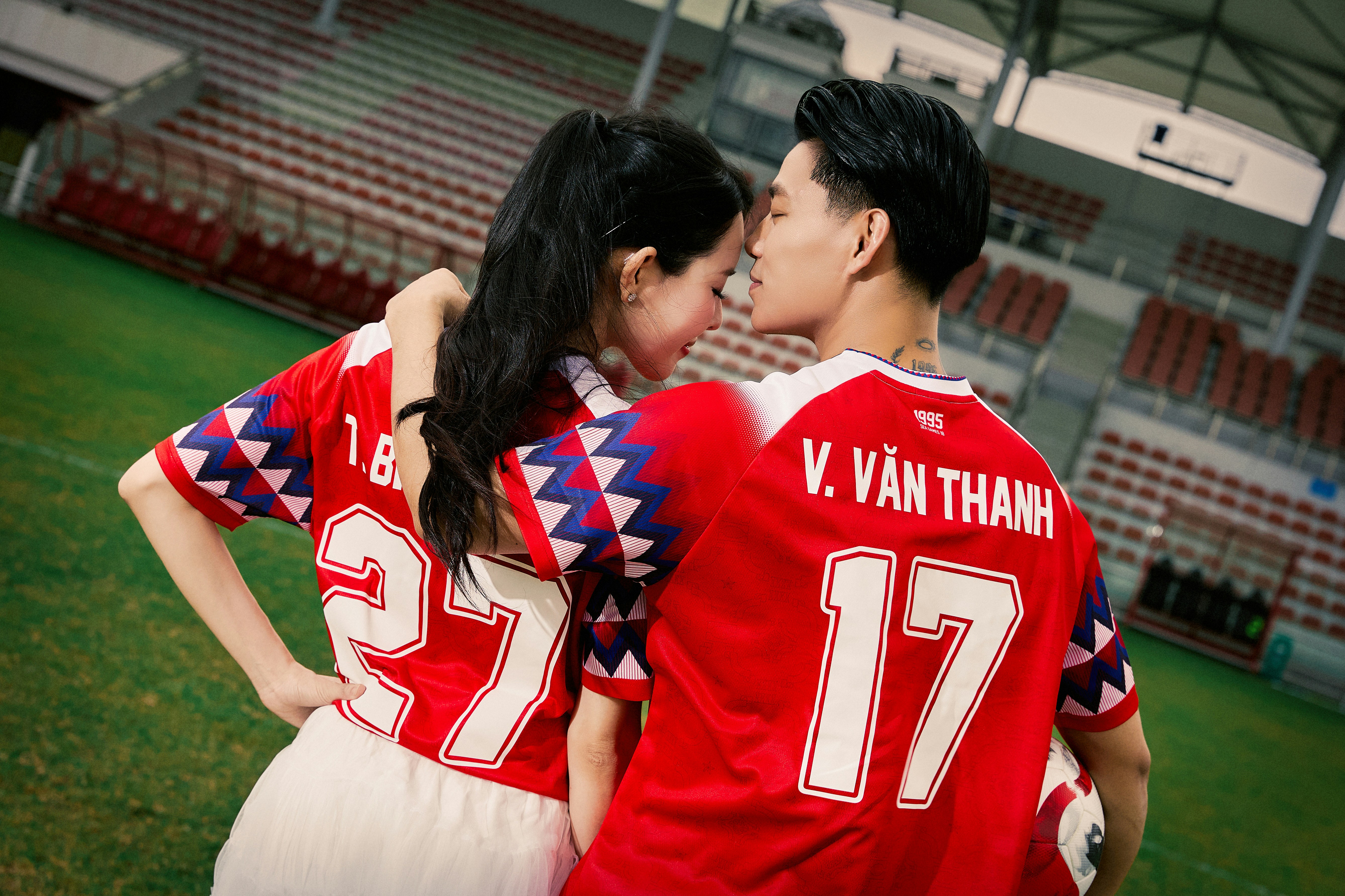 Two people in soccer jerseys embrace on a field.